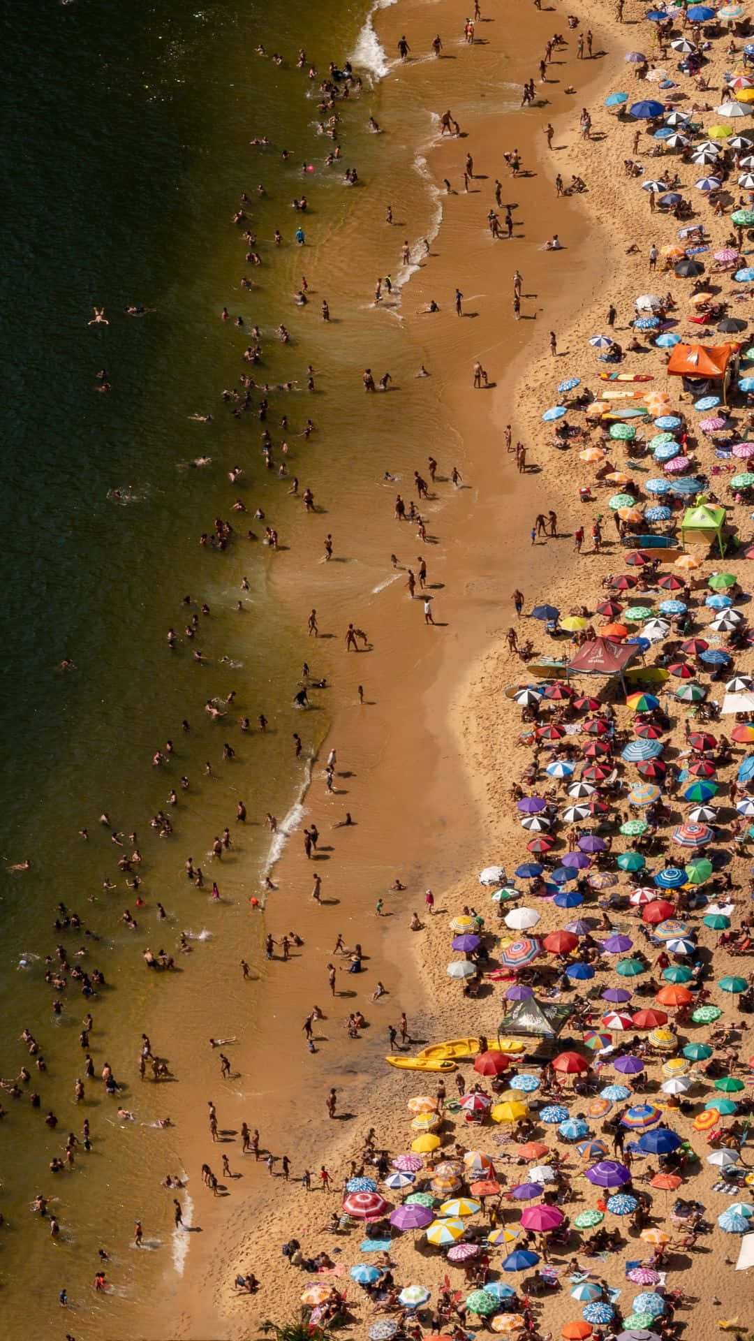 Android Summer 桌布 壁紙 — 擠滿色彩繽紛遮陽傘和游泳者的海灘鳥瞰圖，海水呈藍綠色。