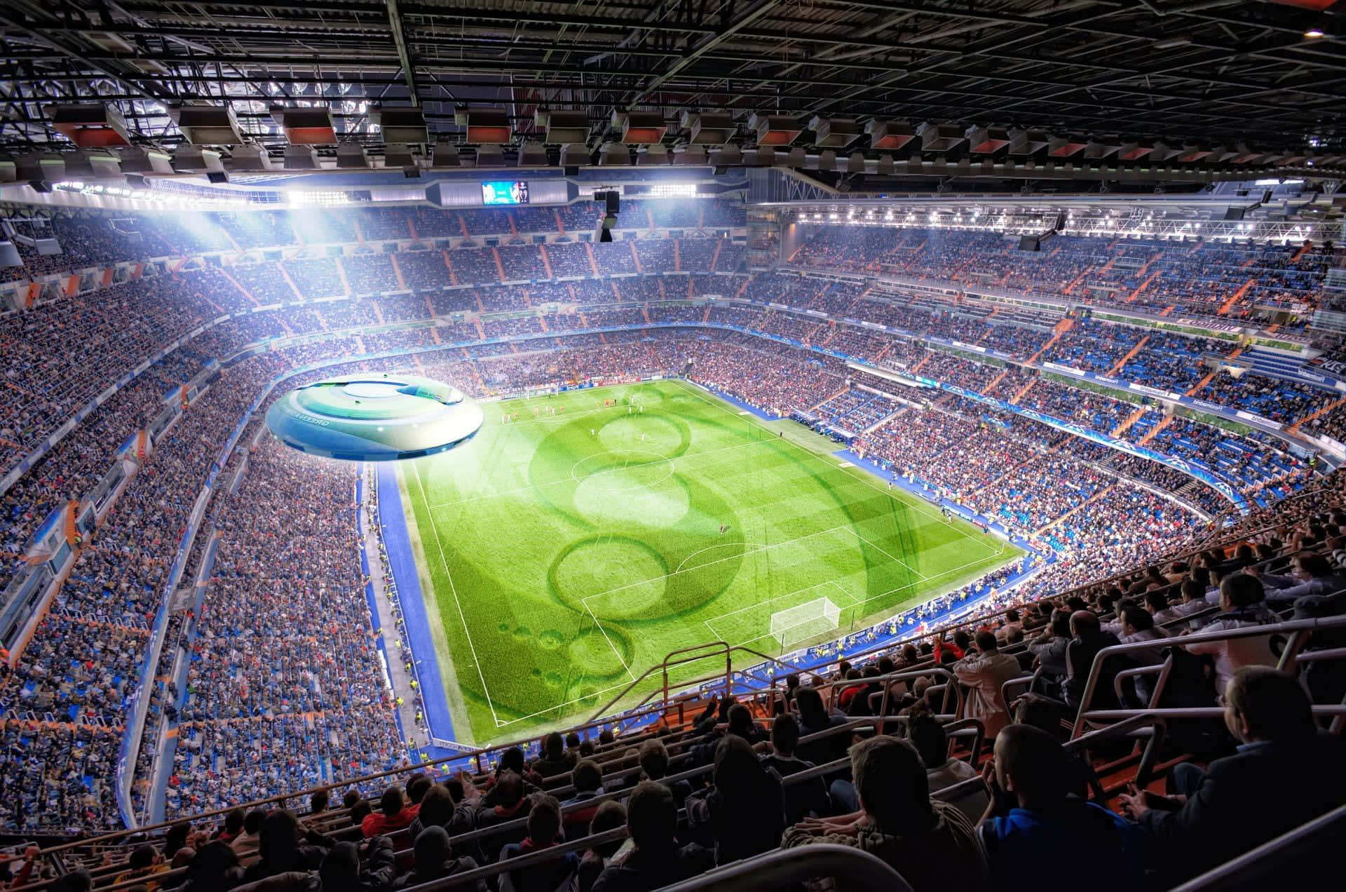 Funny Fantasy Football 桌布 壁紙 — 擠滿觀眾的足球場鳥瞰圖，翠綠的草地和明亮的燈光下，球迷們熱情歡呼。