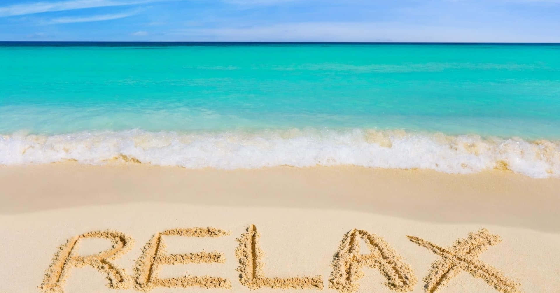 Relax 桌布 壁紙 — 「放鬆」一詞寫在純淨沙灘的沙子上，碧綠的海浪在清澈的藍天下翻滾。