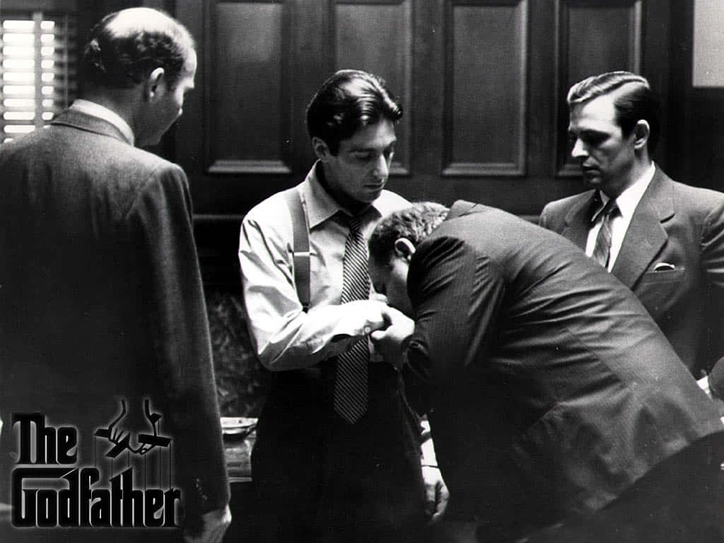 The Godfather 桌布 壁紙 — 《教父》中緊張的黑白場景，顯示穿著西裝的男人在昏暗的房間裡，其中一個男人低下頭，而其他人則專注地看著。