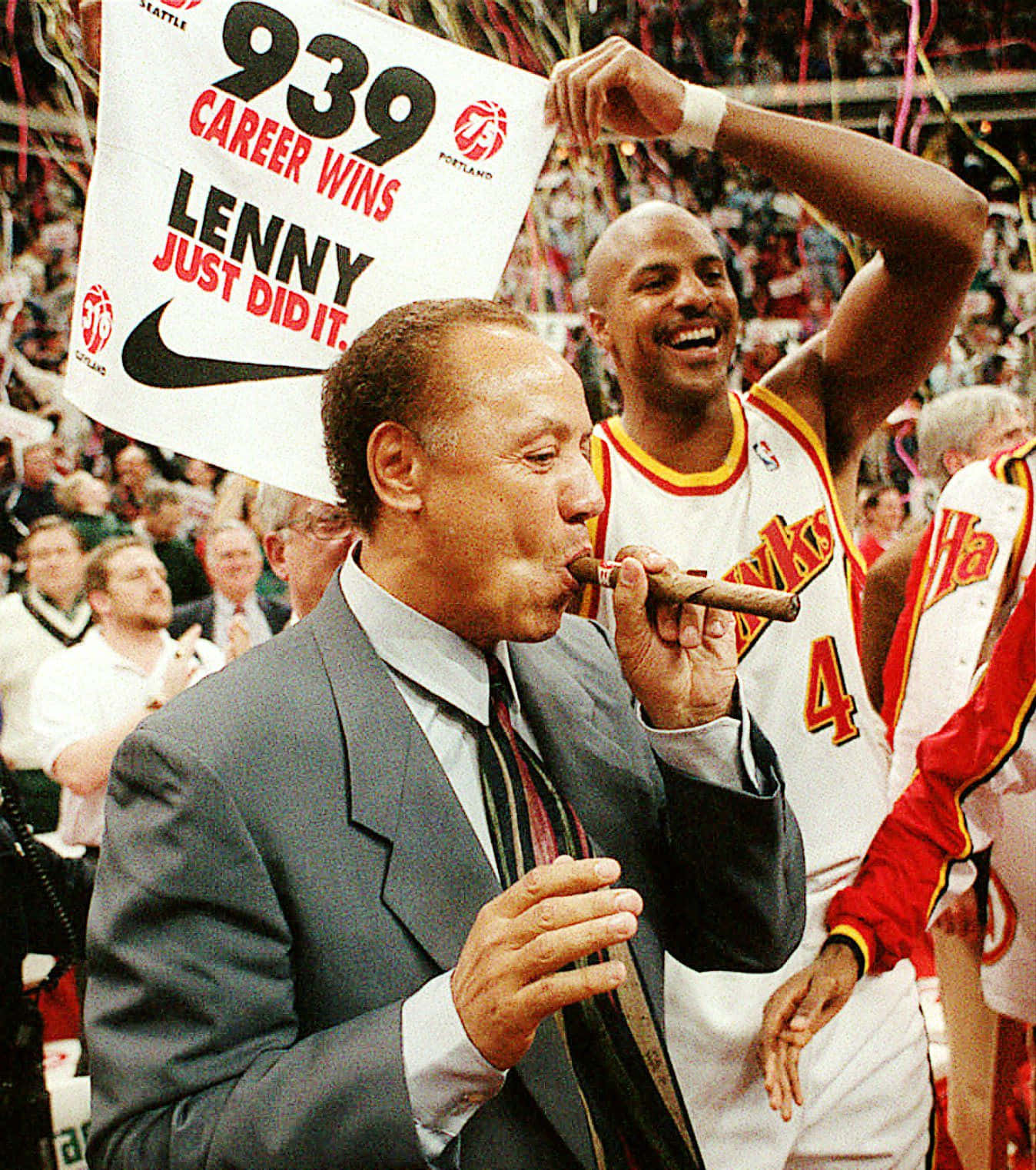 Coach 桌布 壁紙 — 教練Lenny Wilkens抽著雪茄，隊友Dominique Wilkins在擠滿人的場館中舉著「939場職業生涯勝利」的橫幅慶祝。