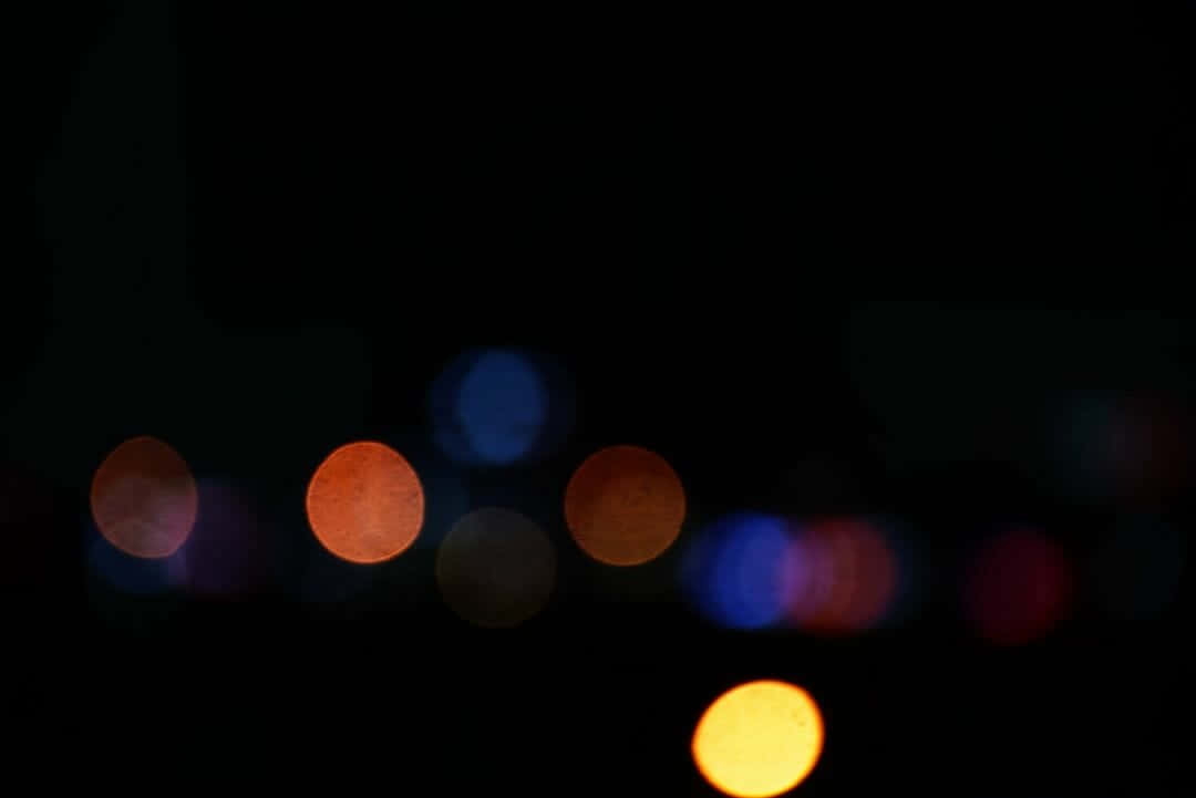 Black Blur 桌布 壁紙 — 散景燈光在深黑色的夜空下溫暖地發光，營造出夢幻的城市夜景。
