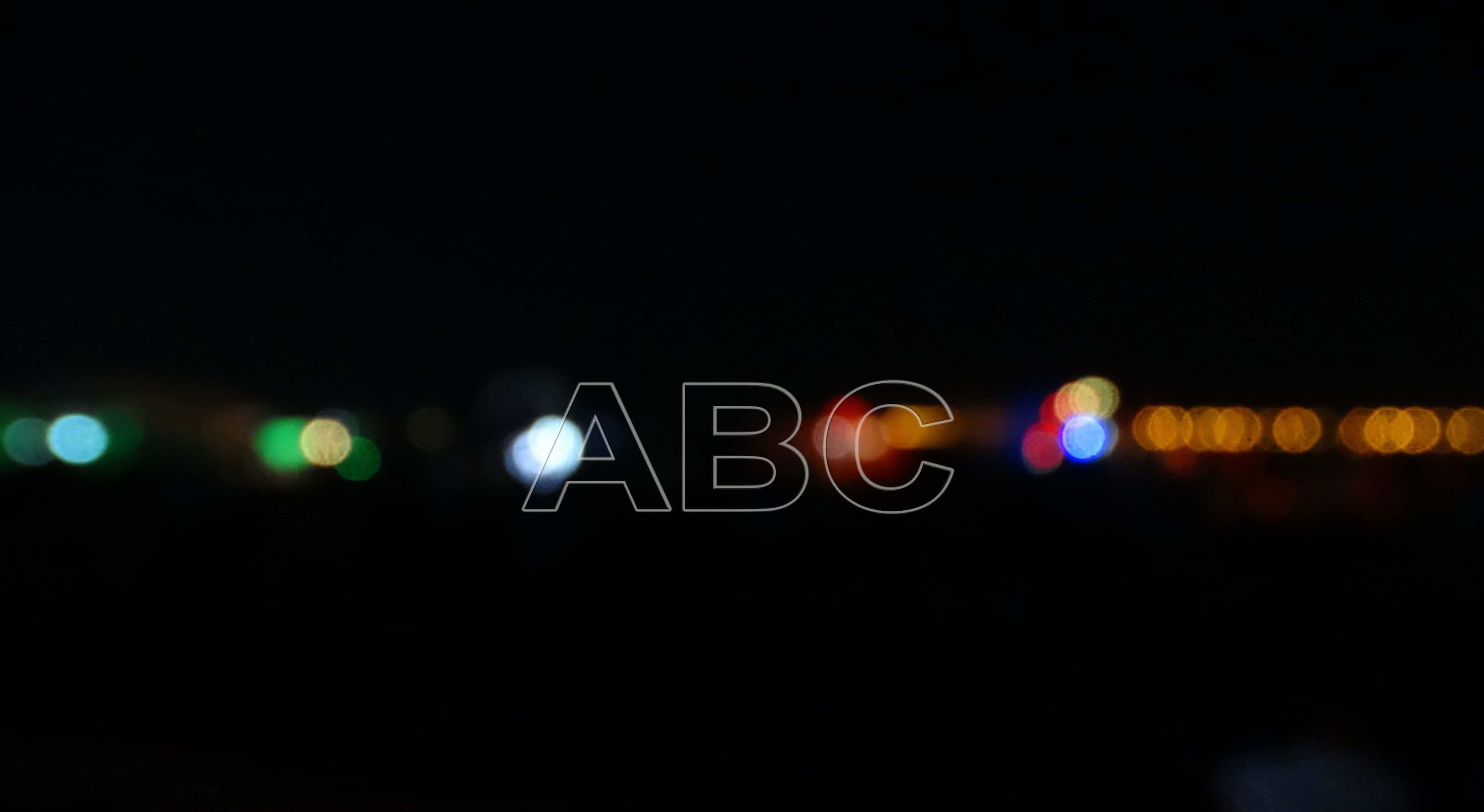 abc 桌布 壁紙 — 散景燈光在漆黑的夜空中柔和發光，帶有微弱的ABC浮水印疊加。