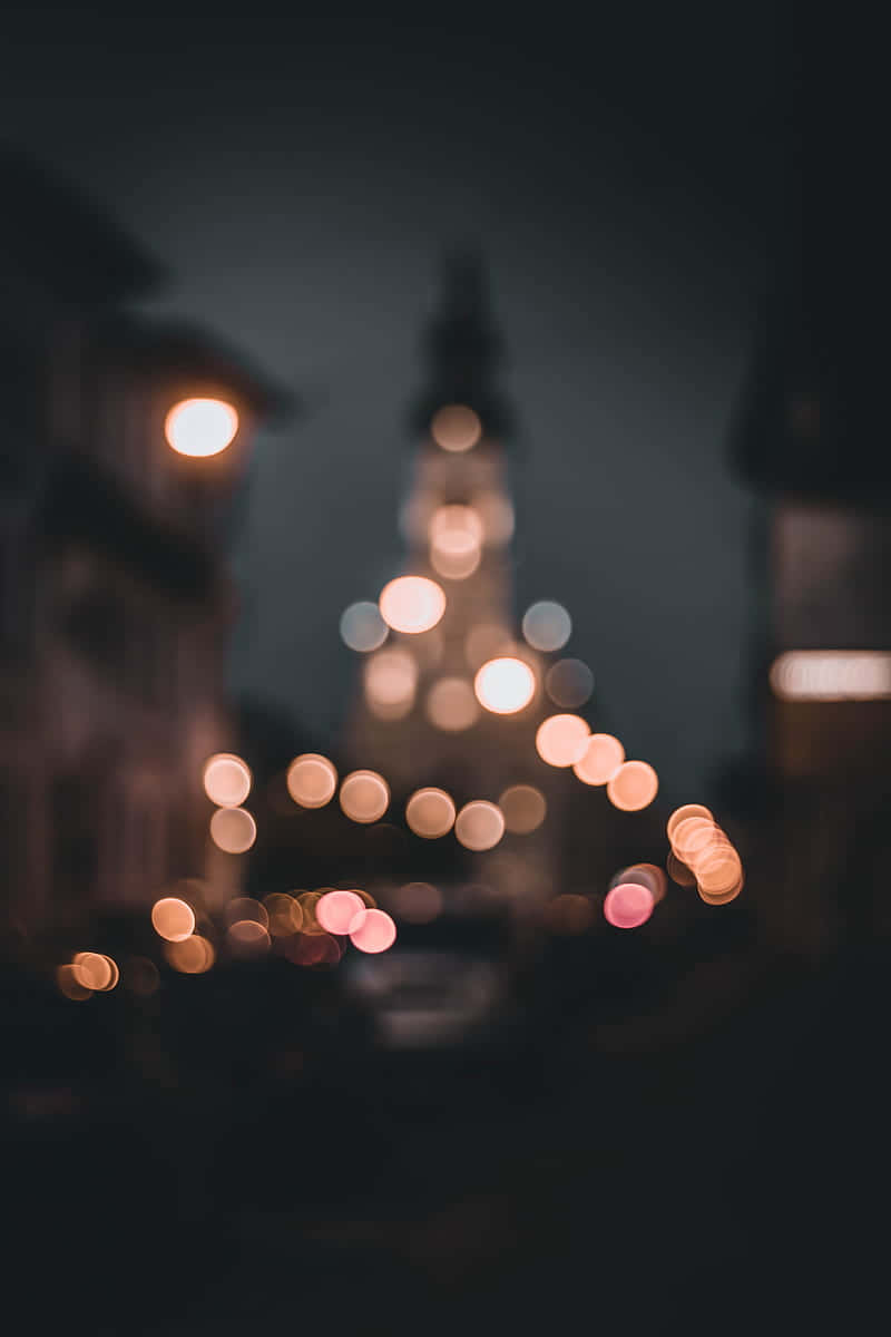 Black Phone 桌布 壁紙 — 散景燈光在黑暗的城市夜空下溫暖地發光，遠處有模糊的教堂尖塔。
