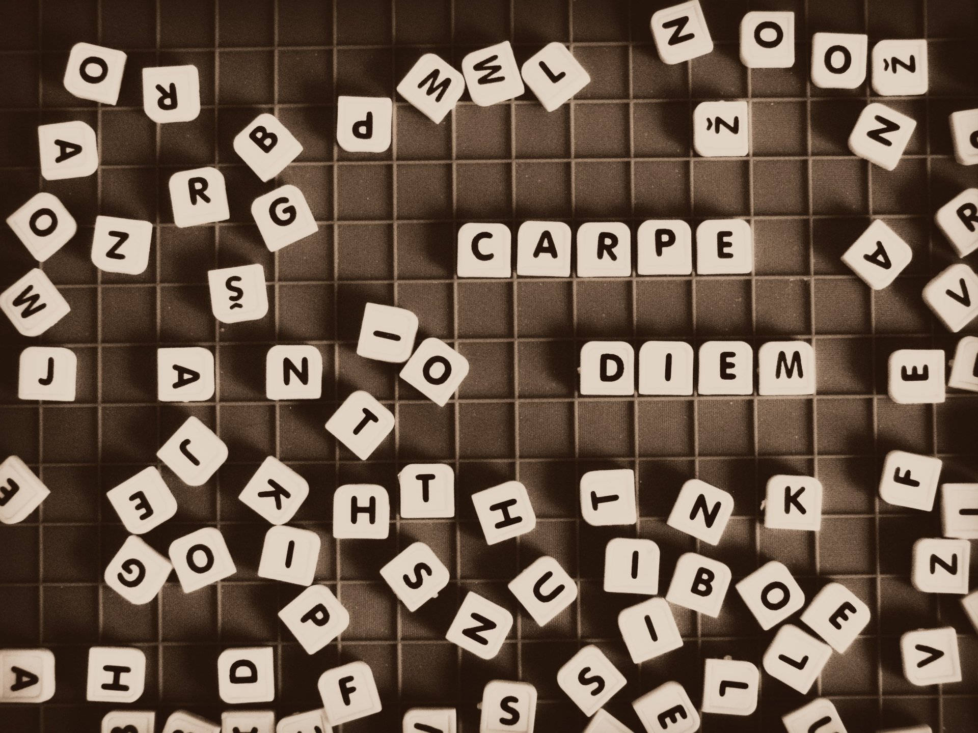 abc 桌布 壁紙 — 散落在網格上的字母瓷磚以懷舊棕色調拼出「CARPE DIEM」，周圍散落著字母。
