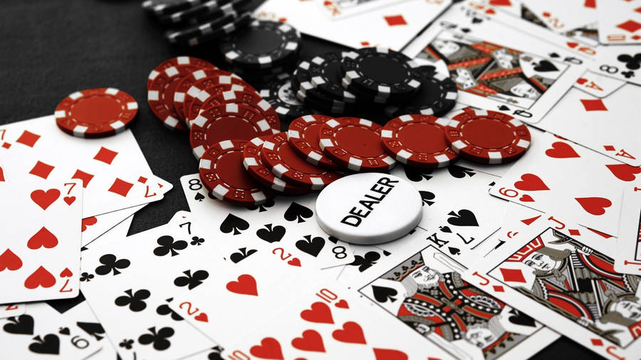 Poker 桌布 壁紙 — 散落的撲克牌和紅黑色籌碼，附有莊家按鈕，在深色表面上。