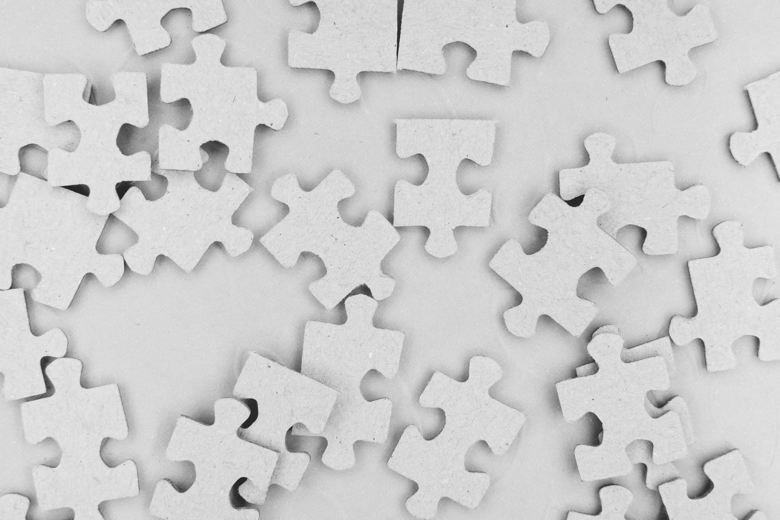 Puzzle 桌布 壁紙 — 散落的白色拼圖碎片以混亂但有序的圖案躺在淺灰色表面上。
