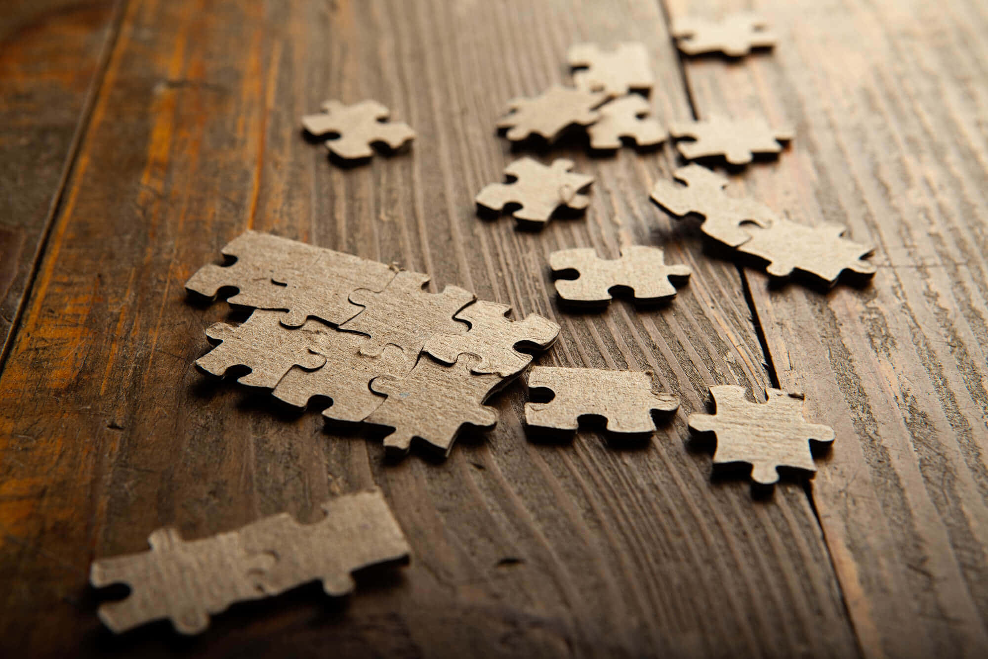 Puzzle 桌布 壁紙 — 散落的米色拼圖碎片放置在具有豐富木紋紋理的風化木質表面上。
