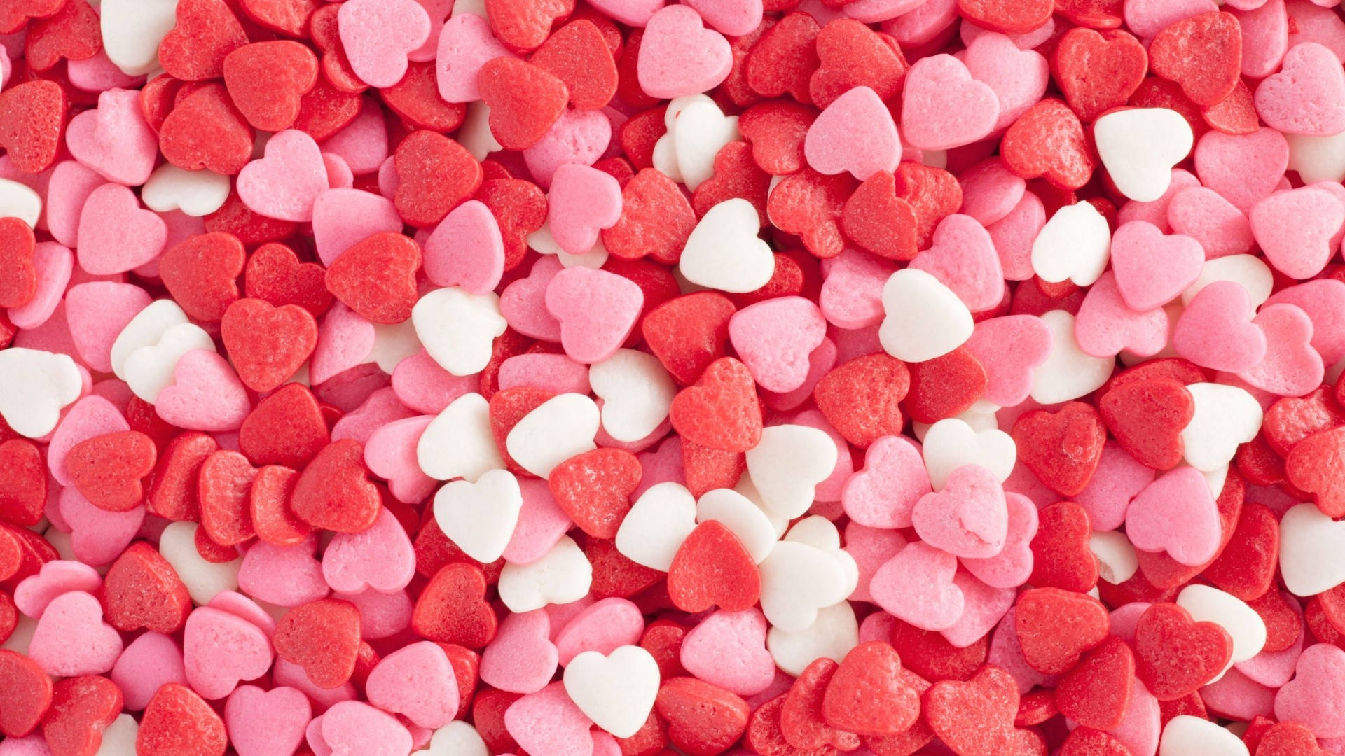 Pastel Pink Heart 桌布 壁紙 — 散落的紅色、粉紅色和白色心形糖粒特寫，營造出甜蜜浪漫的質感。