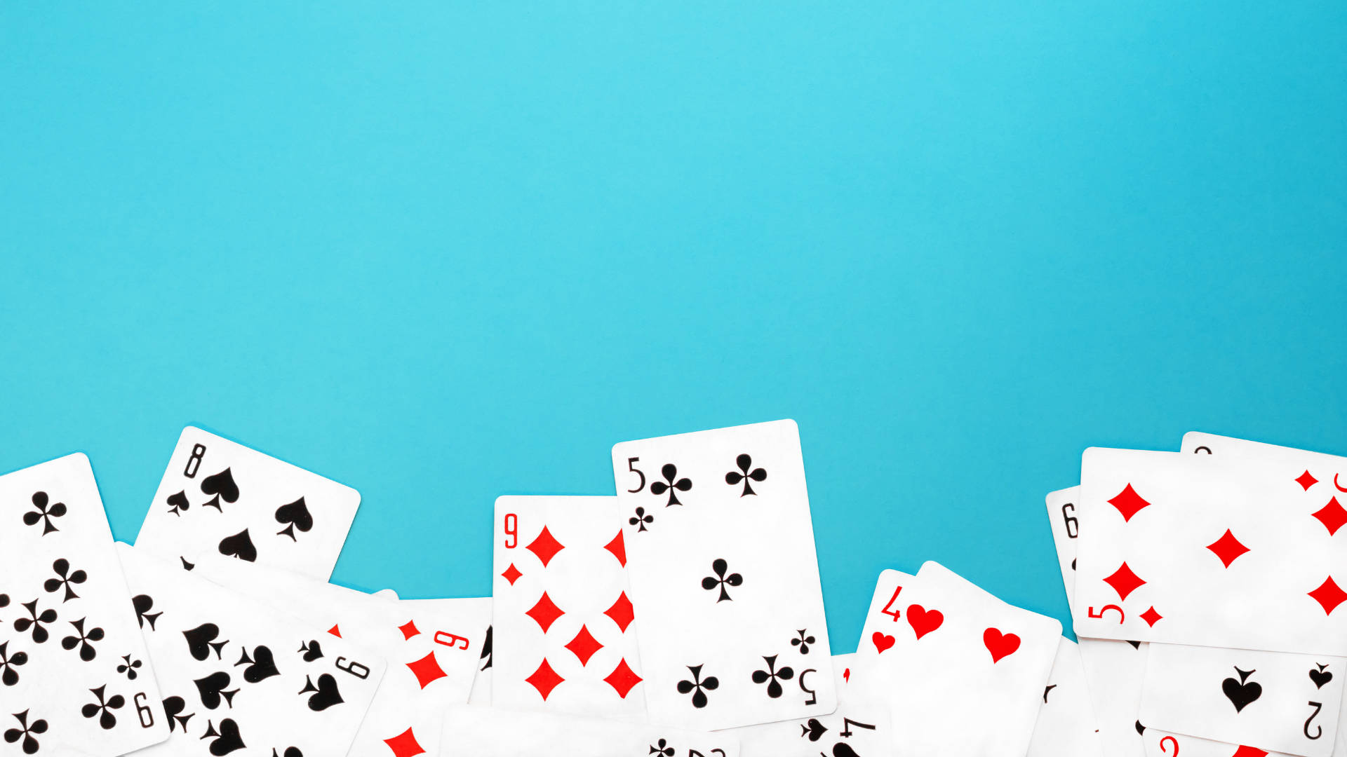 Playing Cards 桌布 壁紙 — 散落的紅黑花色撲克牌排列在純色藍綠色背景上。