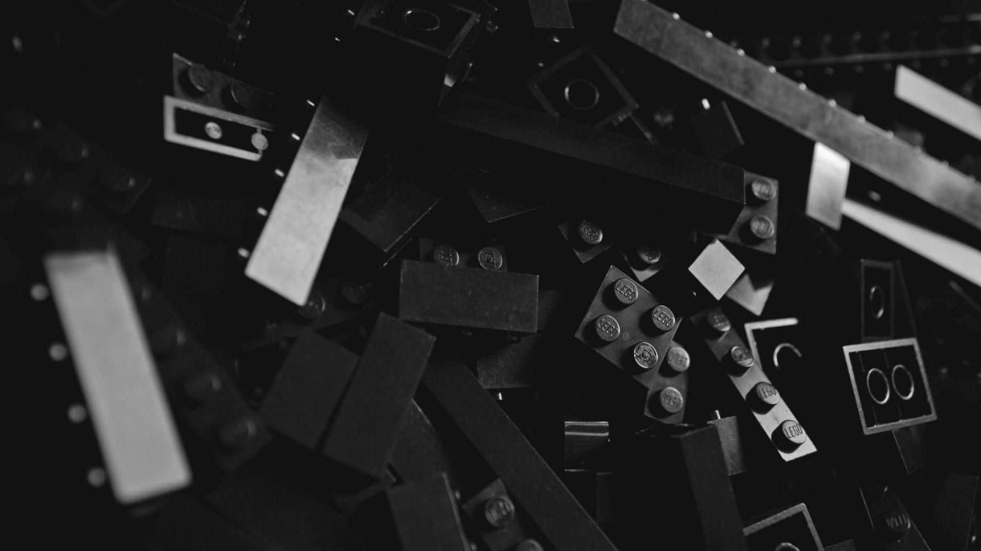樂高 桌布 壁紙 — 散落的黑色LEGO積木和零件的單色特寫，形成有紋理的抽象構圖。
