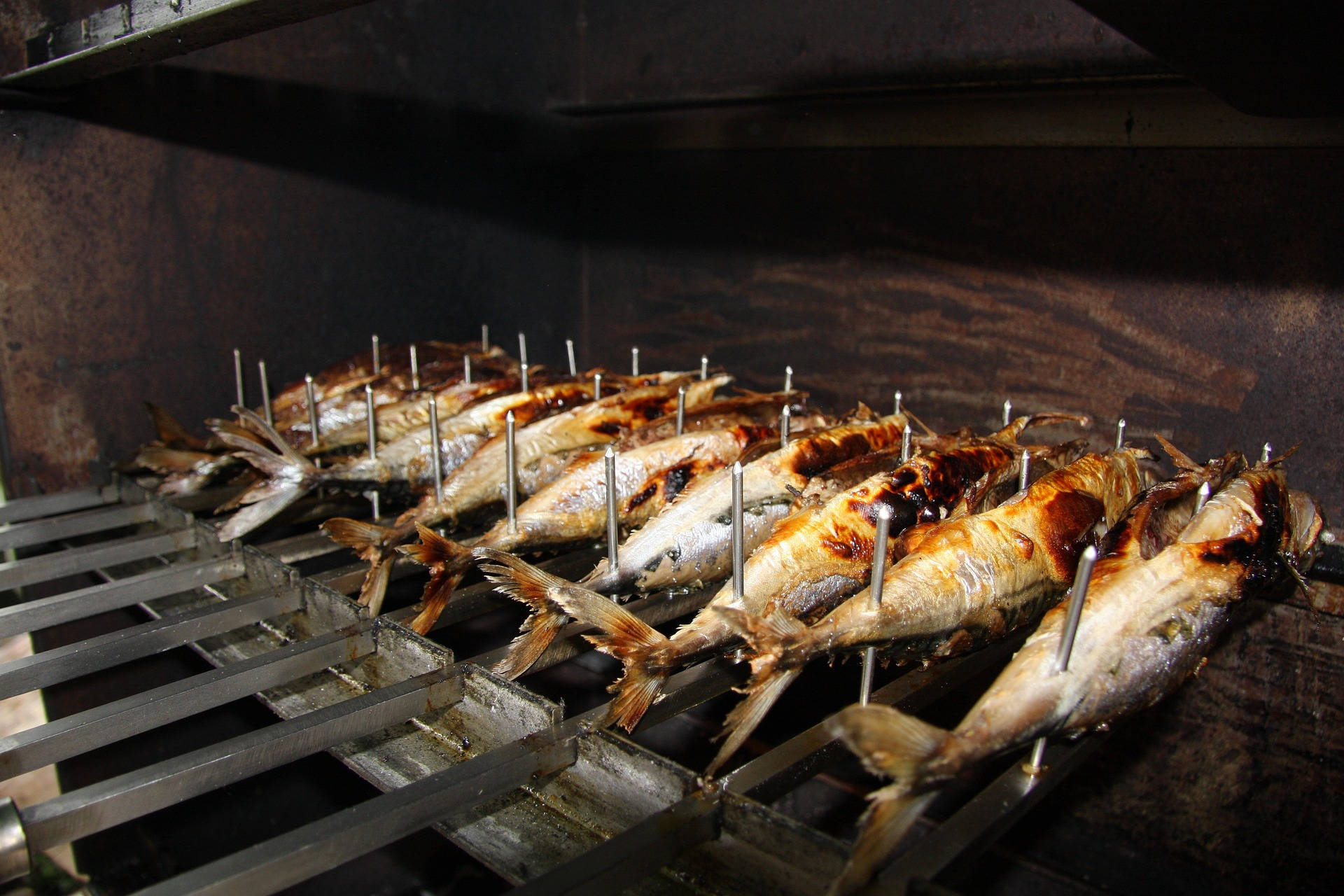 魚 桌布 壁紙 — 整條魚用金屬串串起，在鄉村式煙燻爐內的金屬烤架上滋滋作響。
