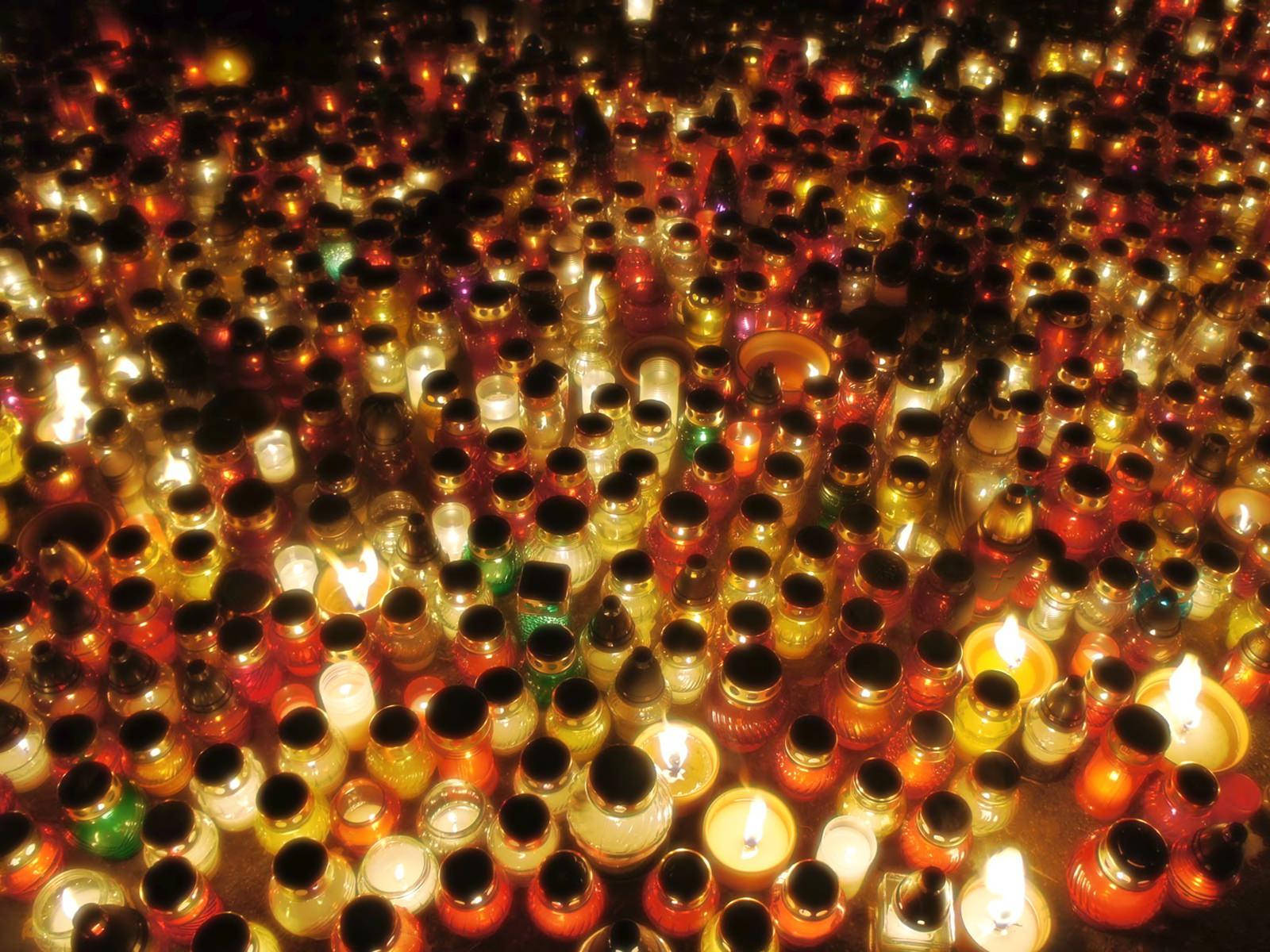 All Saints Day 桌布 壁紙 — 數千個玻璃罐中的發光蠟燭在夜晚營造出溫暖閃爍的光芒之海。