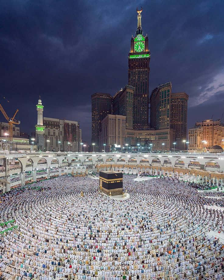 Mecca Kaaba 桌布 壁紙 — 數千名身穿白衣的朝聖者在漆黑的天空下，圍繞著被發光的阿布拉吉阿爾拜特鐘樓照亮的卡巴天房轉圈。