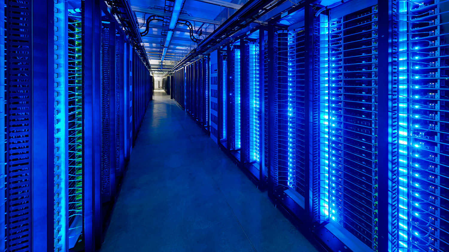 Gaming Servers 桌布 壁紙 — 數據中心內一條長長的伺服器機架走廊，發出藍色光芒。