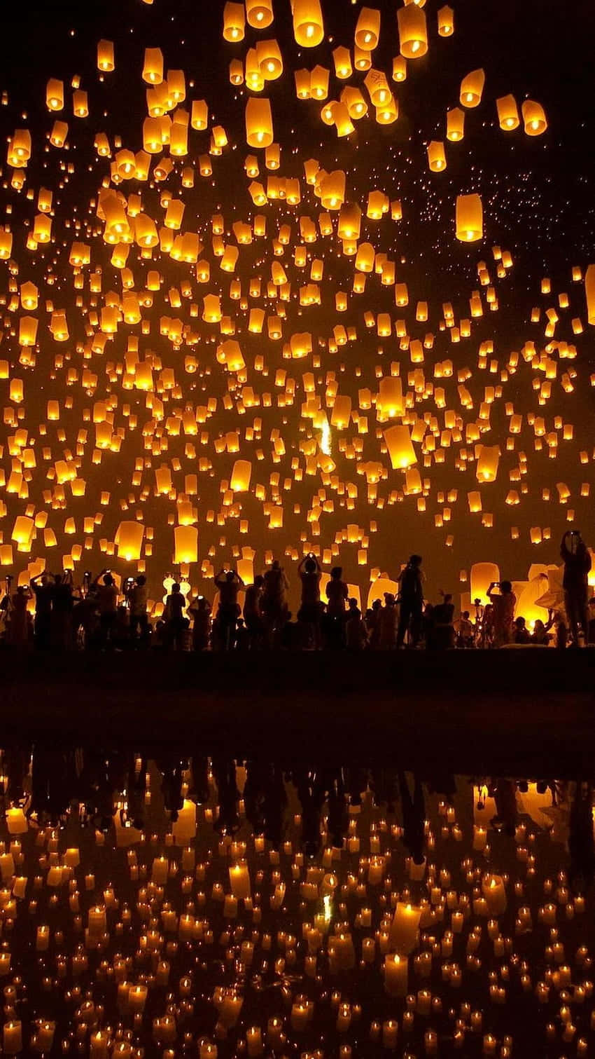Lantern 桌布 壁紙 — 數百盞發光的天燈在夜間升起，映襯著剪影的人們，完美地倒映在下方平靜的水面上。