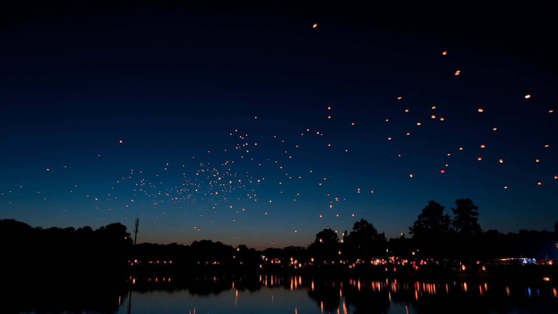 Aesthetic Night Sky 桌布 壁紙 — 數百盞發光的燈籠在黃昏時分漂浮在平靜的湖面上，在水面上投下溫暖的倒影。