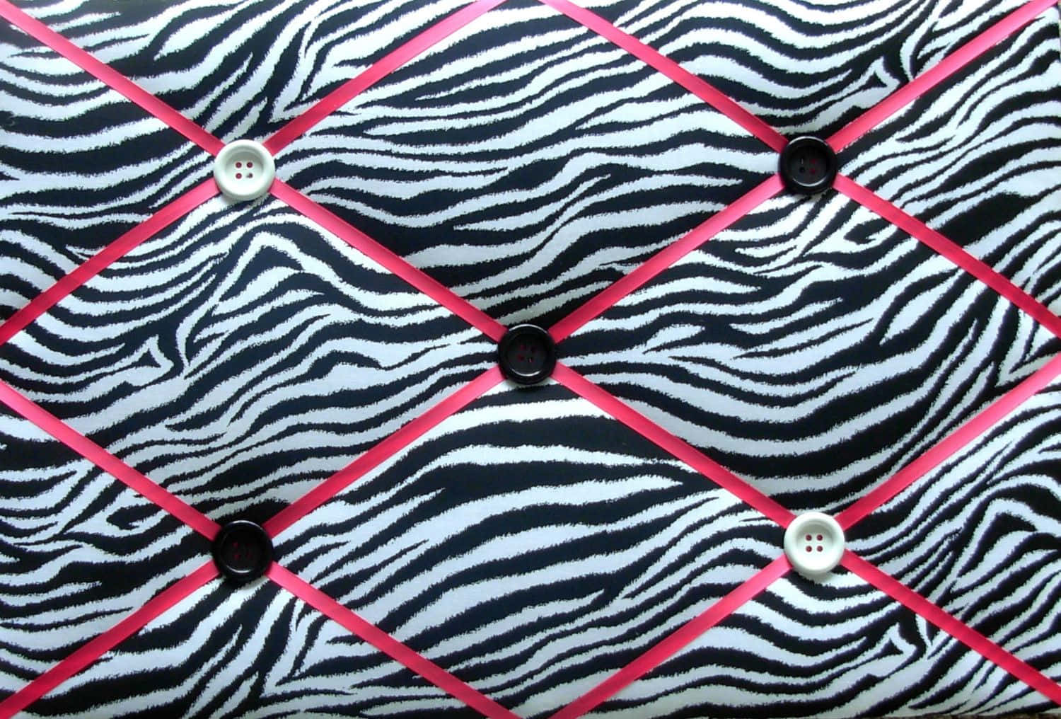 Animal Print 桌布 壁紙 — 斑馬紋布料，飾有鮮明的粉紅色絲帶和對比強烈的黑白鈕扣，形成菱形網格圖案。