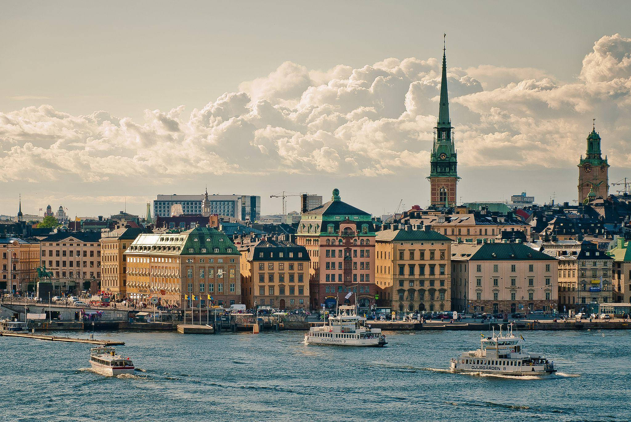 Sweden 桌布 壁紙 — 斯德哥爾摩歷史悠久的海濱全景，色彩繽紛的建築物和船隻在陰天之下。