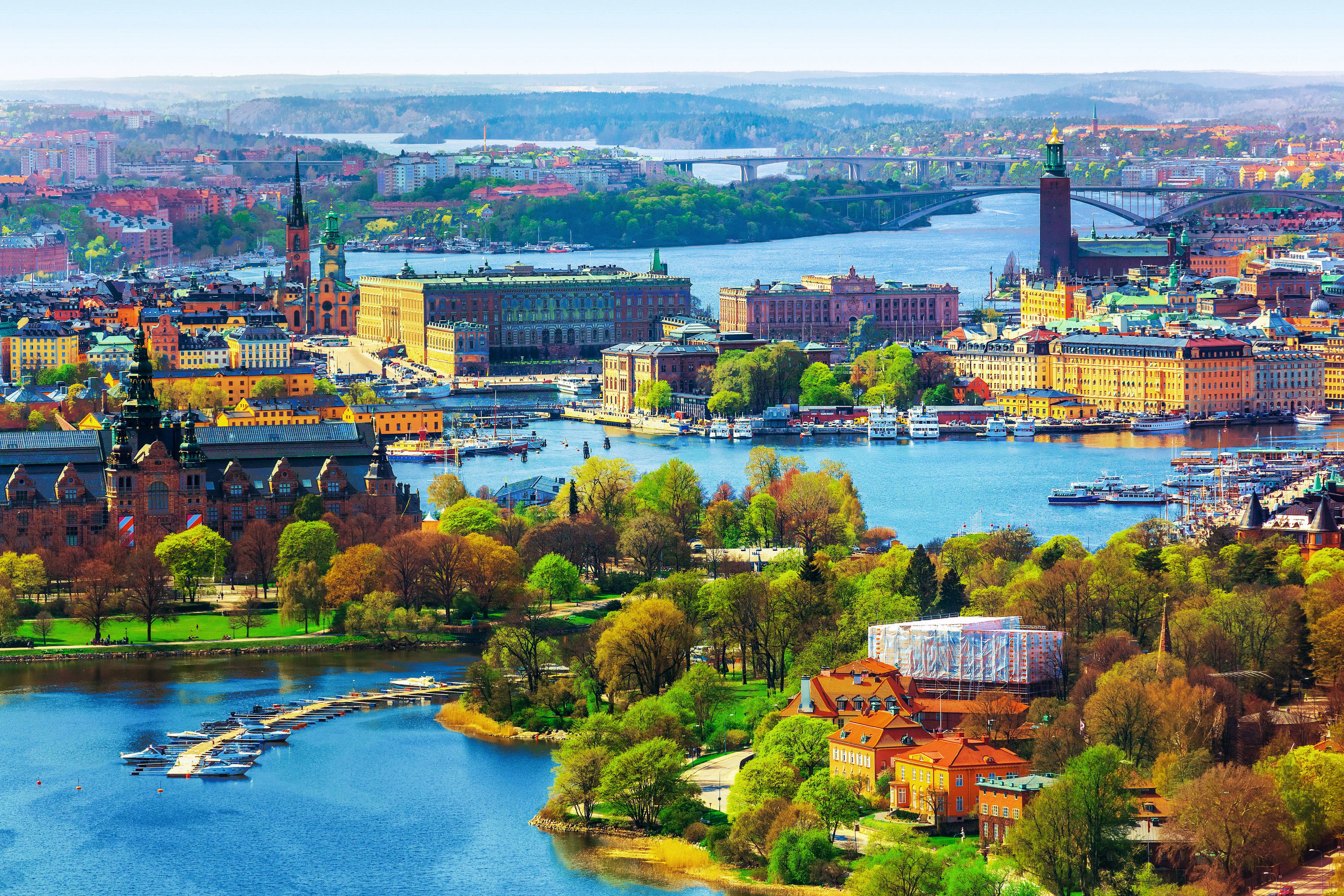 Sweden 桌布 壁紙 — 斯德哥爾摩歷史悠久的濱水區鳥瞰圖，色彩繽紛的建築物、橋樑和船隻在晴朗的天空下。