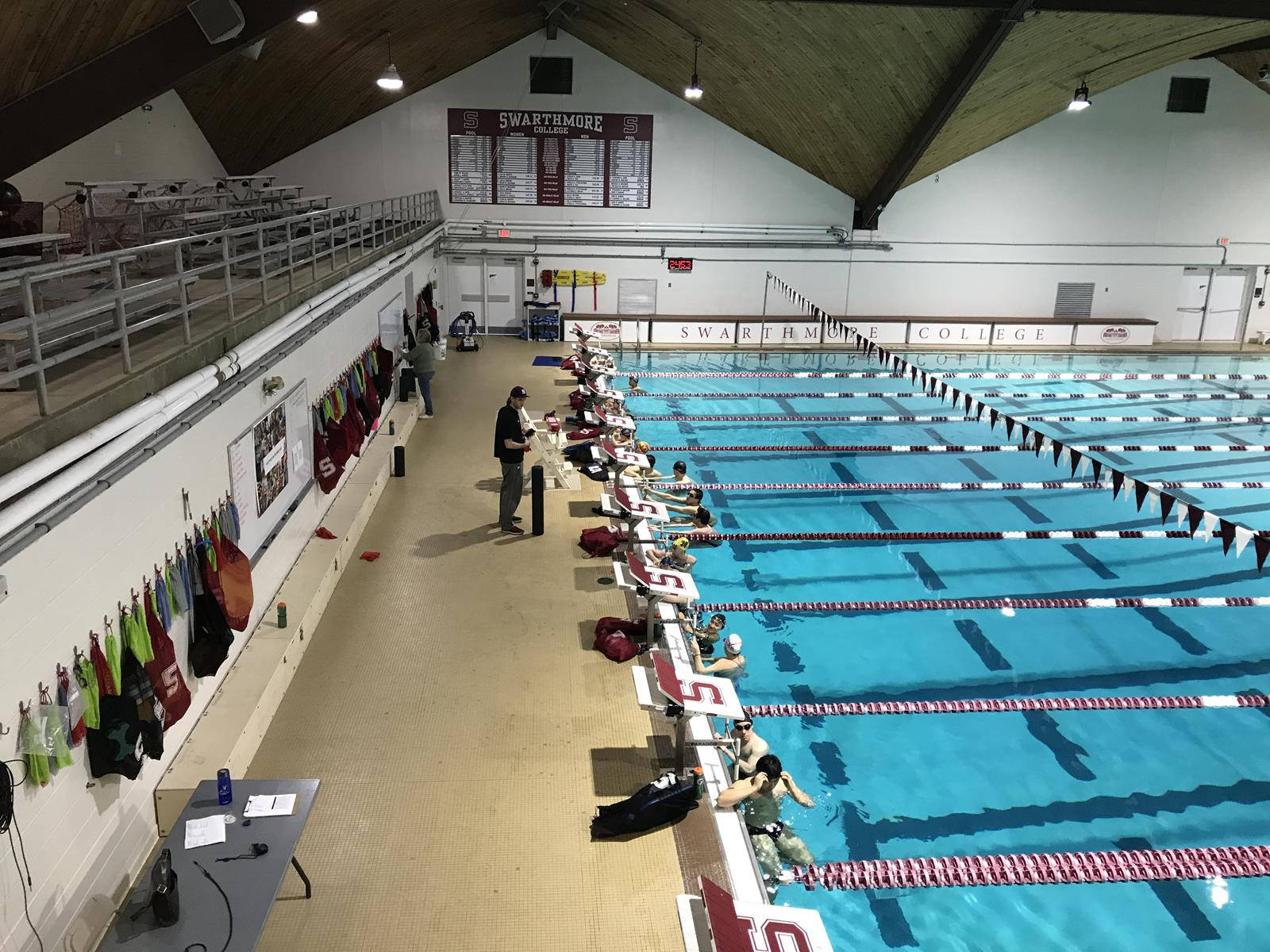pool 桌布 壁紙 — 斯沃斯莫爾學院的室內游泳池，泳道中有游泳者，看台上有觀眾，頭頂有明亮的燈光。