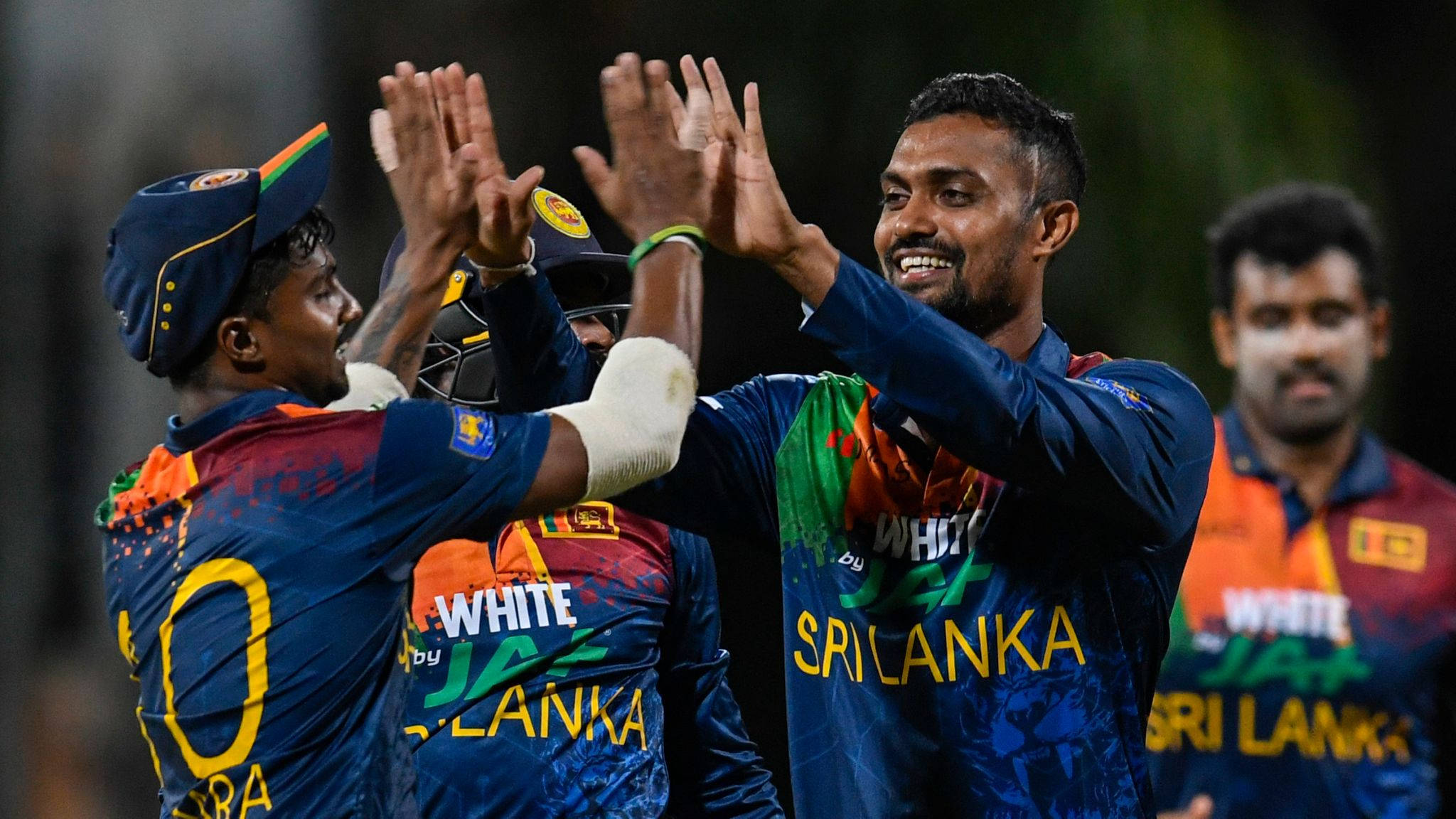 Sri Lanka Cricket 桌布 壁紙 — 斯里蘭卡板球運動員在夜間比賽期間於體育館燈光下擊掌慶祝。