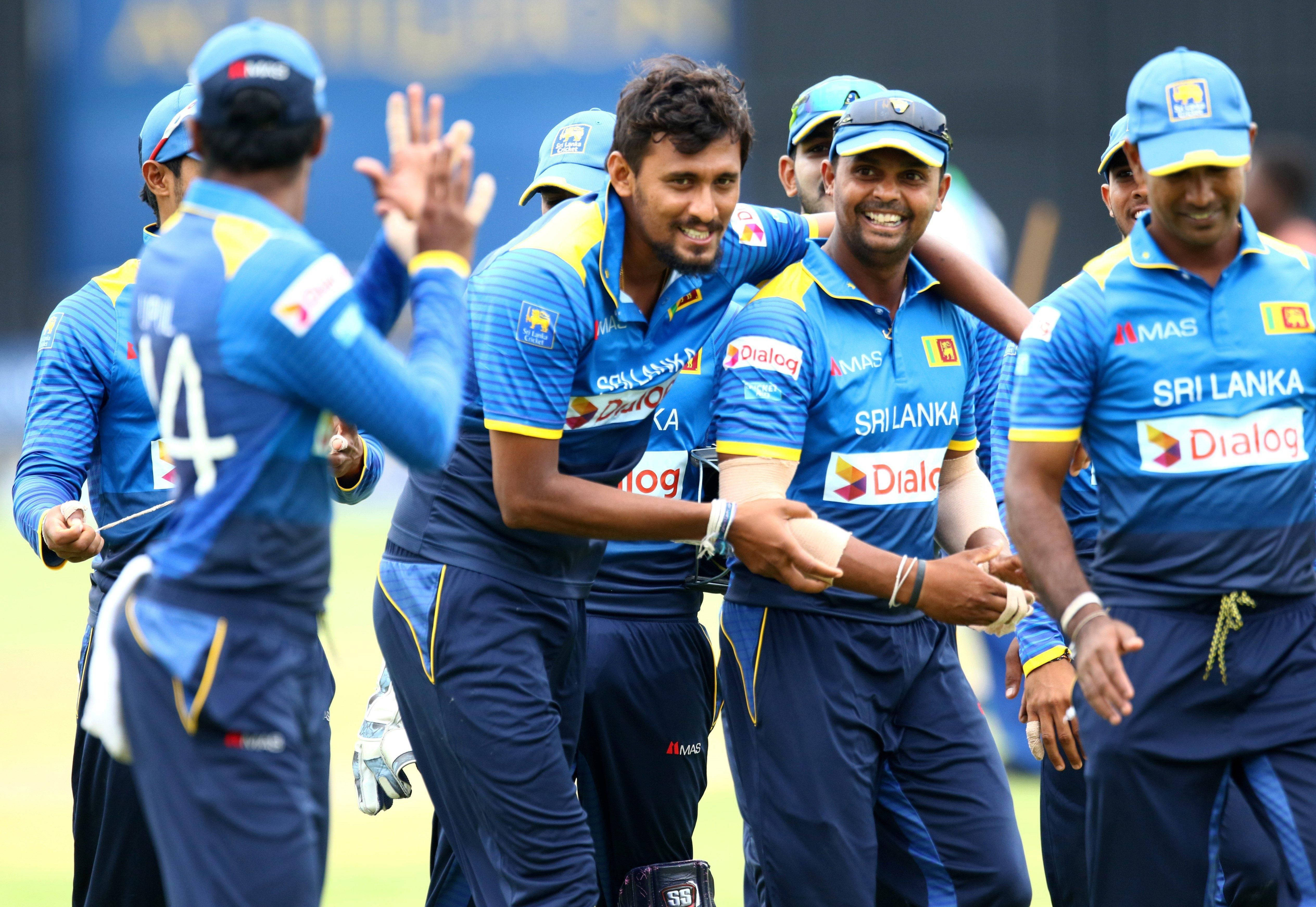 Sri Lanka Cricket 桌布 壁紙 — 斯里蘭卡板球隊球員身穿藍色制服，在陽光明媚的場地上熱情地擊掌慶祝，笑容滿面。