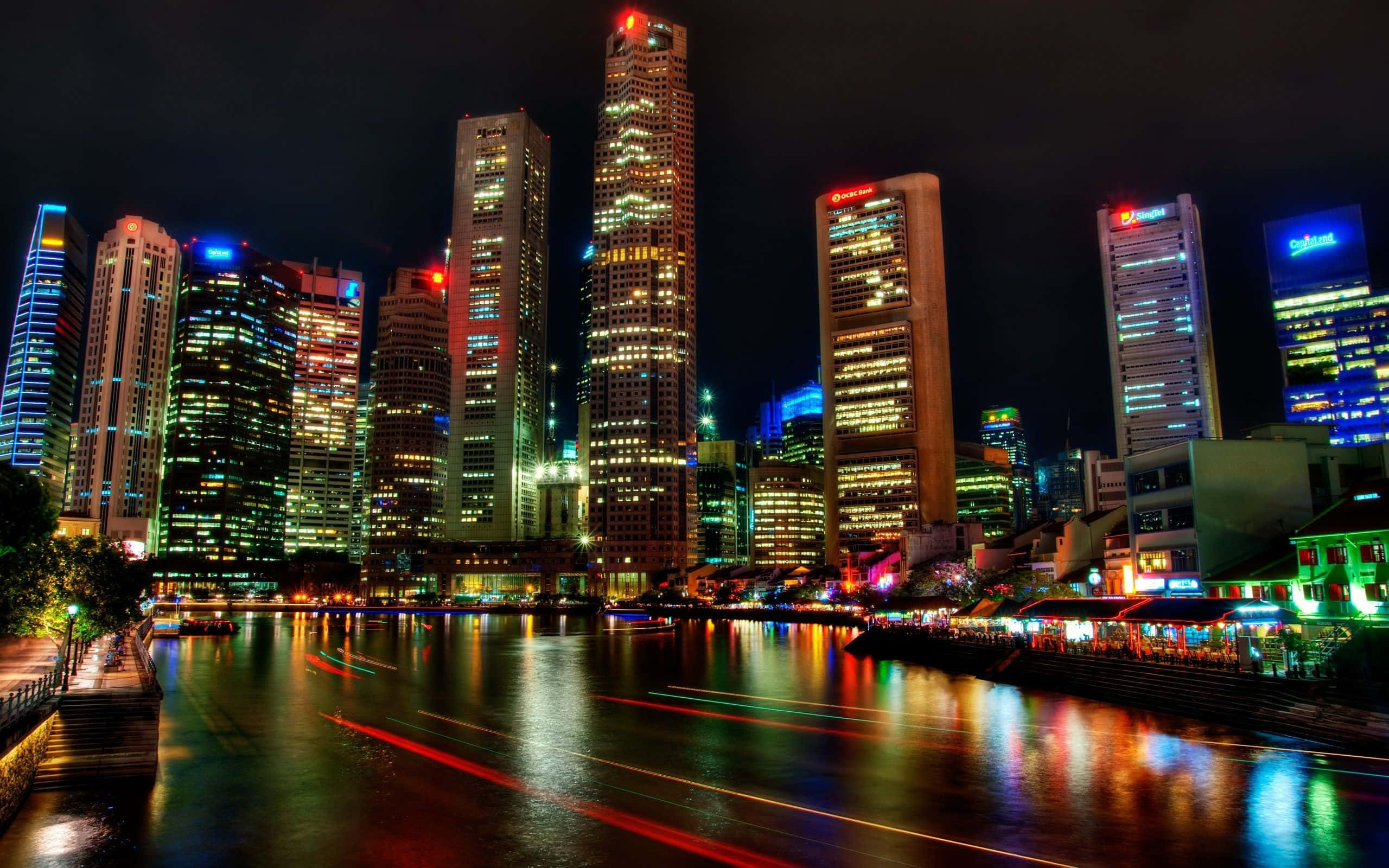 桌布 壁紙 — 新加坡天際線的璀璨夜景，摩天大樓在黑暗的天空中閃耀，燈光倒映在下面的河流中。