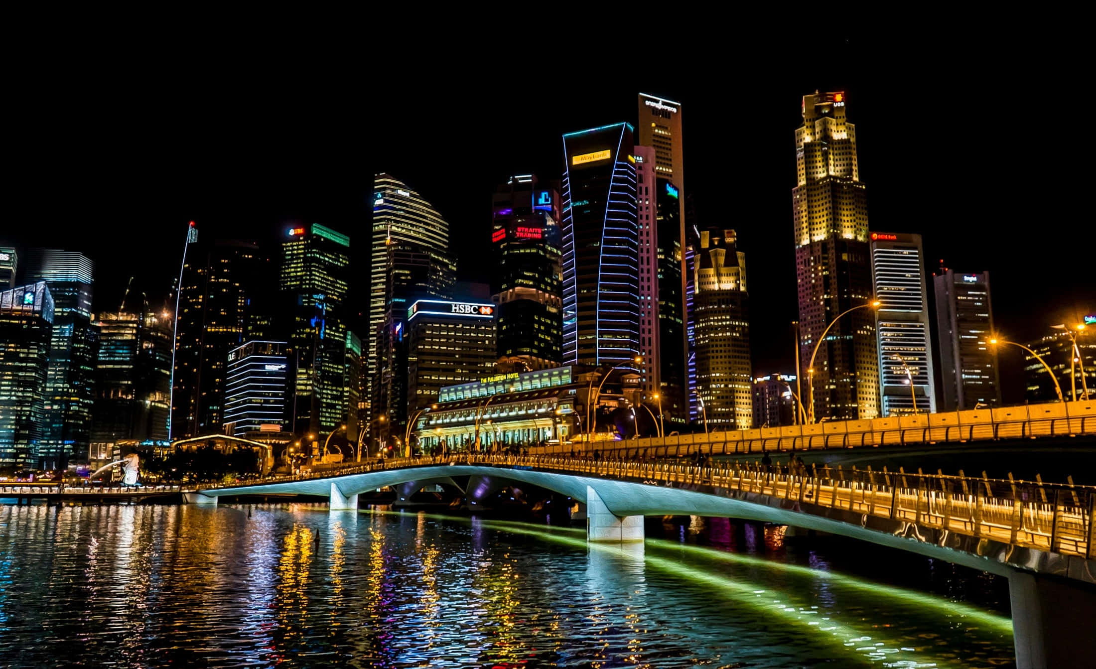 桌布 壁紙 — 新加坡天際線的耀眼夜景，有燈火通明的摩天大樓和在水面上閃閃發光的橋樑。