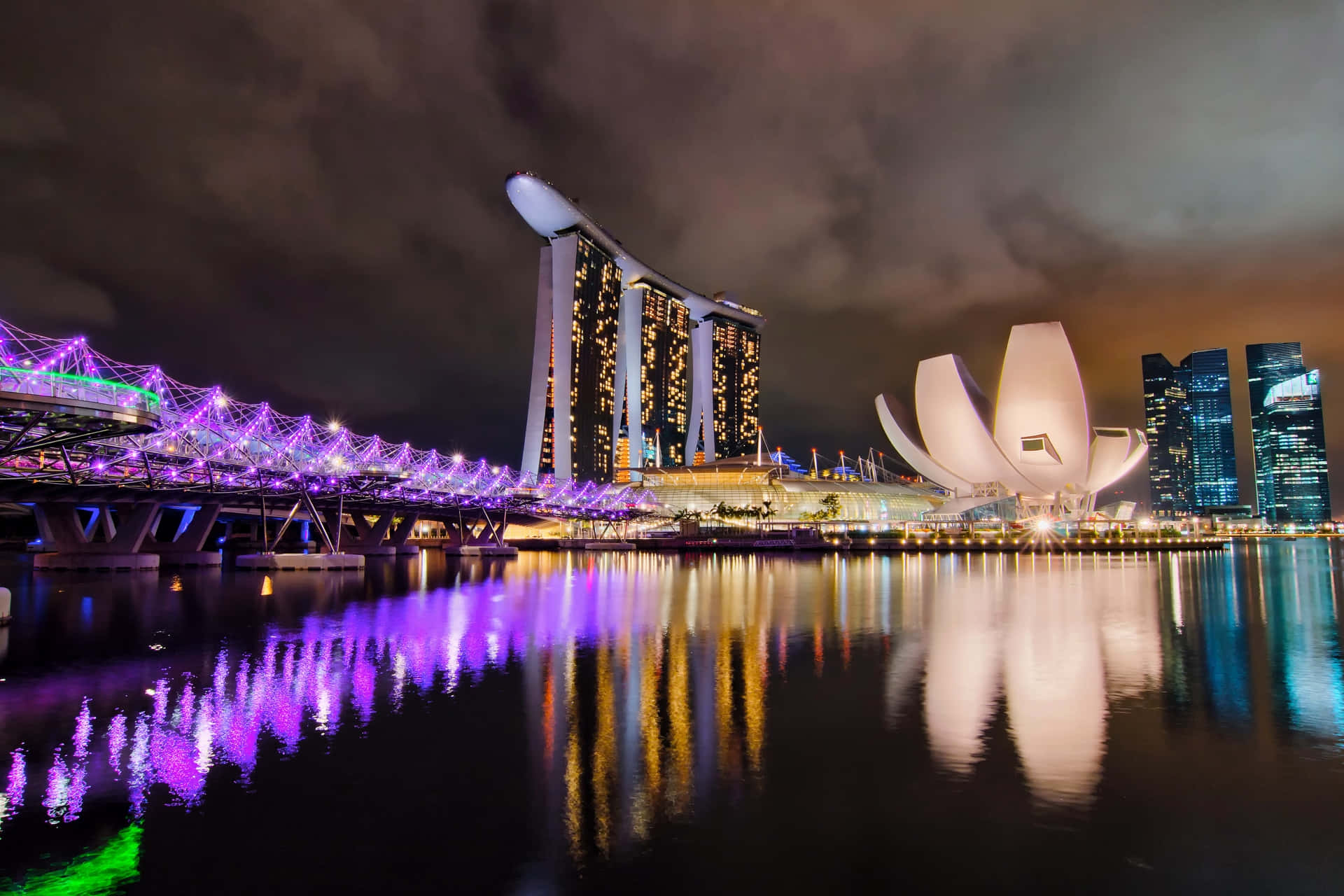 Singapore 桌布 壁紙 — 新加坡天際線的迷人夜景，濱海灣金沙和藝術科學博物館被充滿活力的紫色燈光照亮，倒映在水面上。