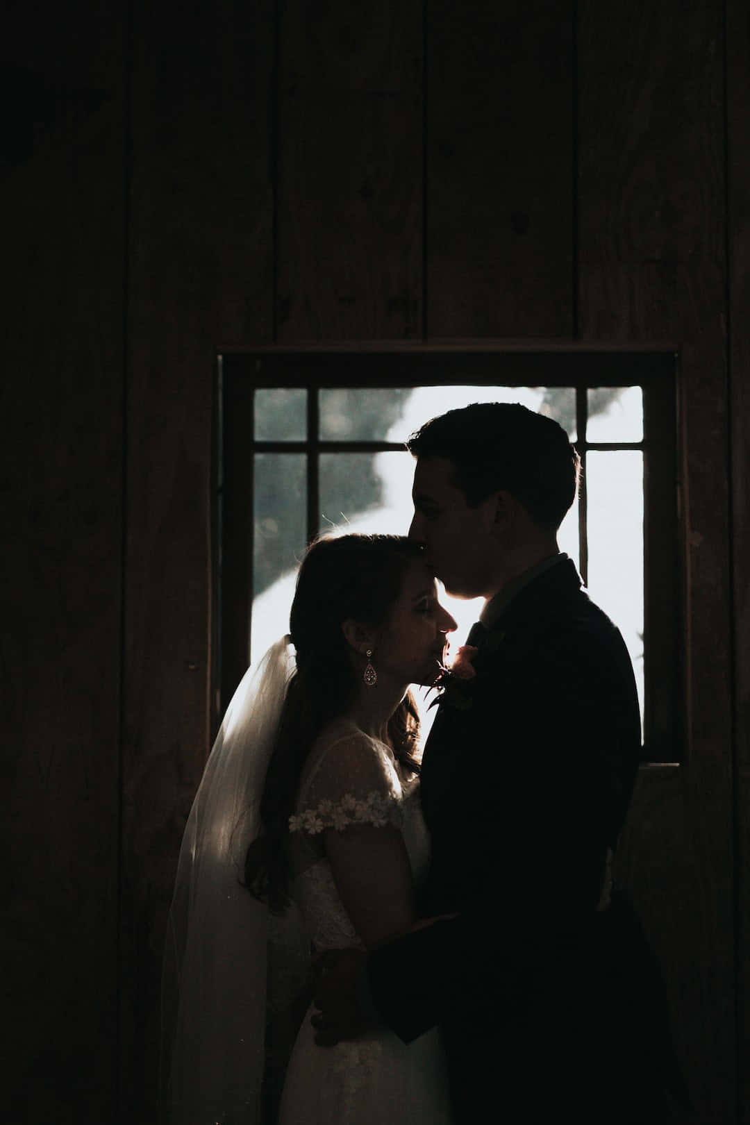 Forehead Kiss 桌布 壁紙 — 新娘和新郎以剪影形式在鄉村木穀倉的陽光窗前溫柔擁抱。