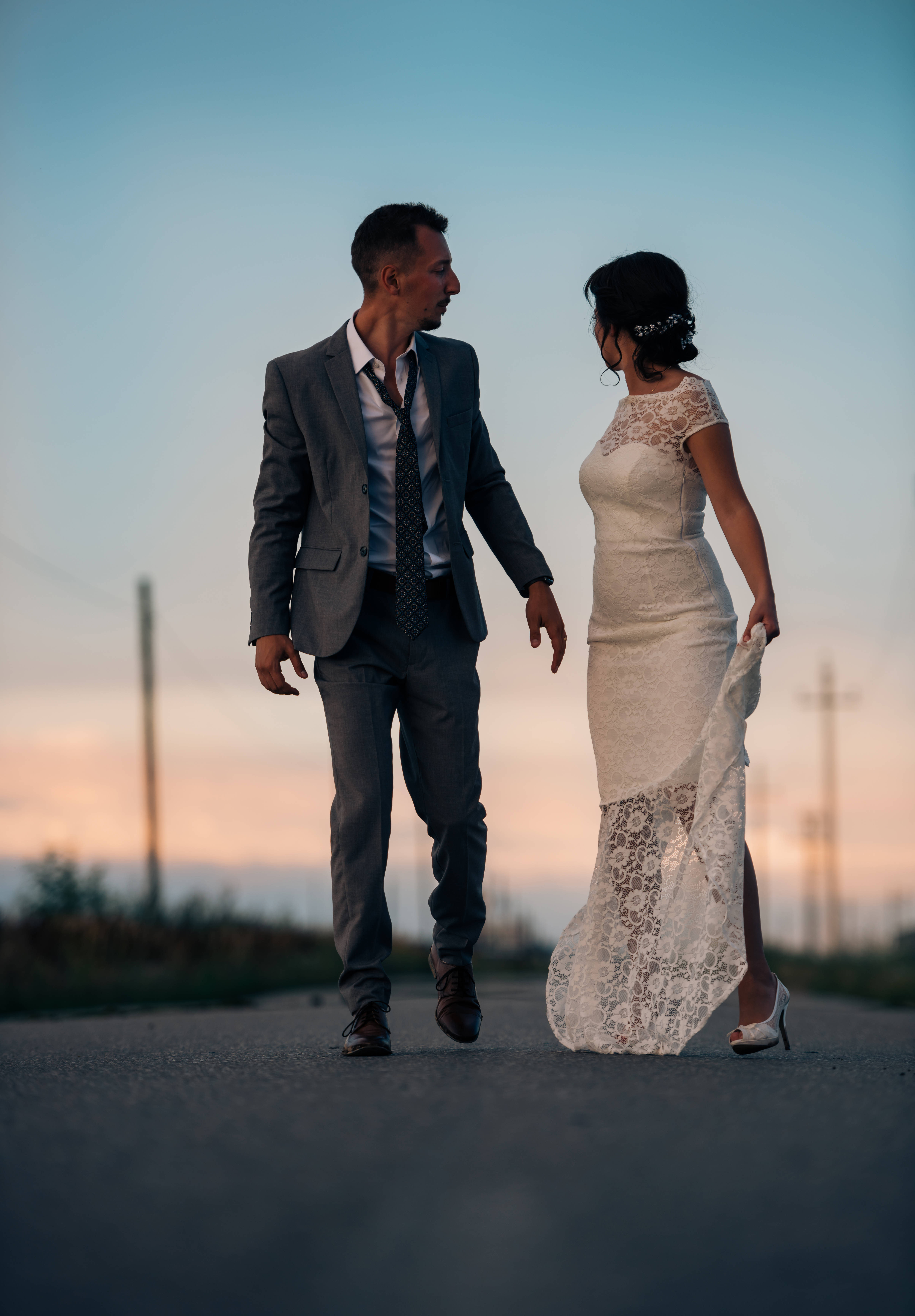 Groom 桌布 壁紙 — 新娘和新郎在日落時分手牽手走在鄉間小路上，他們的剪影被溫暖的金色光芒所環繞。