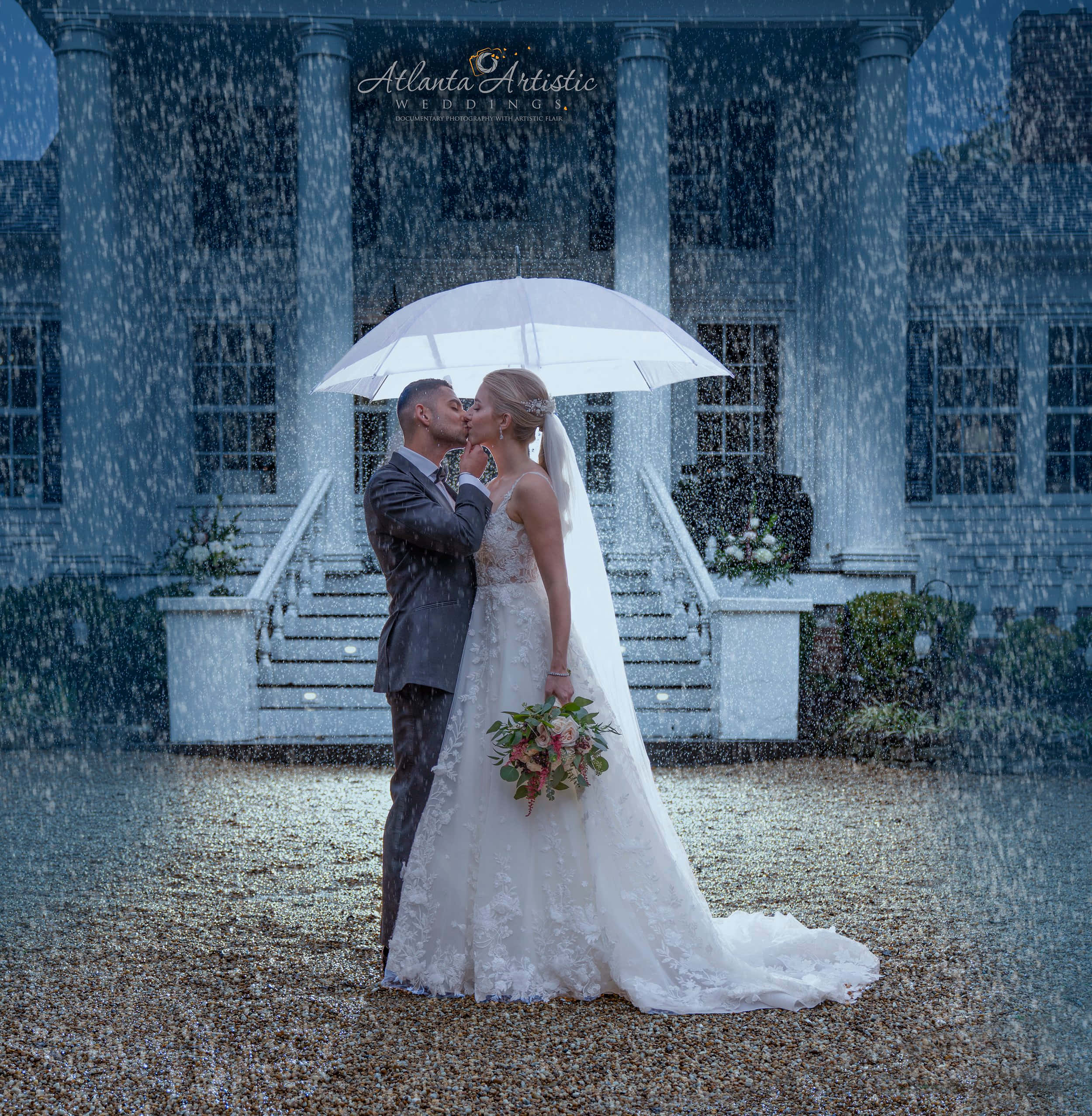 Bride And Groom 桌布 壁紙 — 新娘和新郎在白色雨傘下接吻，大雨傾盆，面前是一座宏偉的大宅。