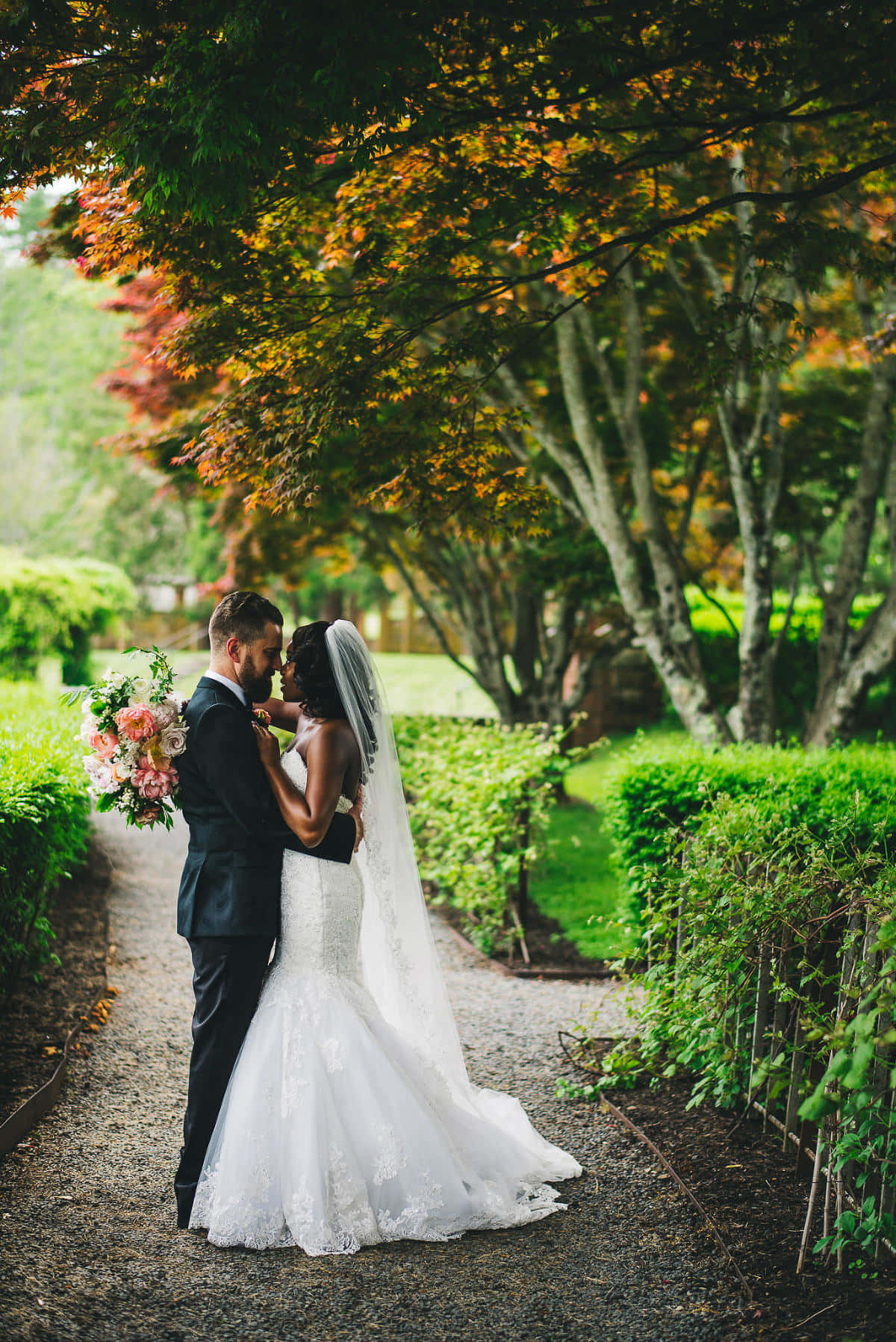 Garden Wedding 桌布 壁紙 — 新娘和新郎在色彩鮮豔的橙色和綠色秋葉樹冠下溫柔擁抱。
