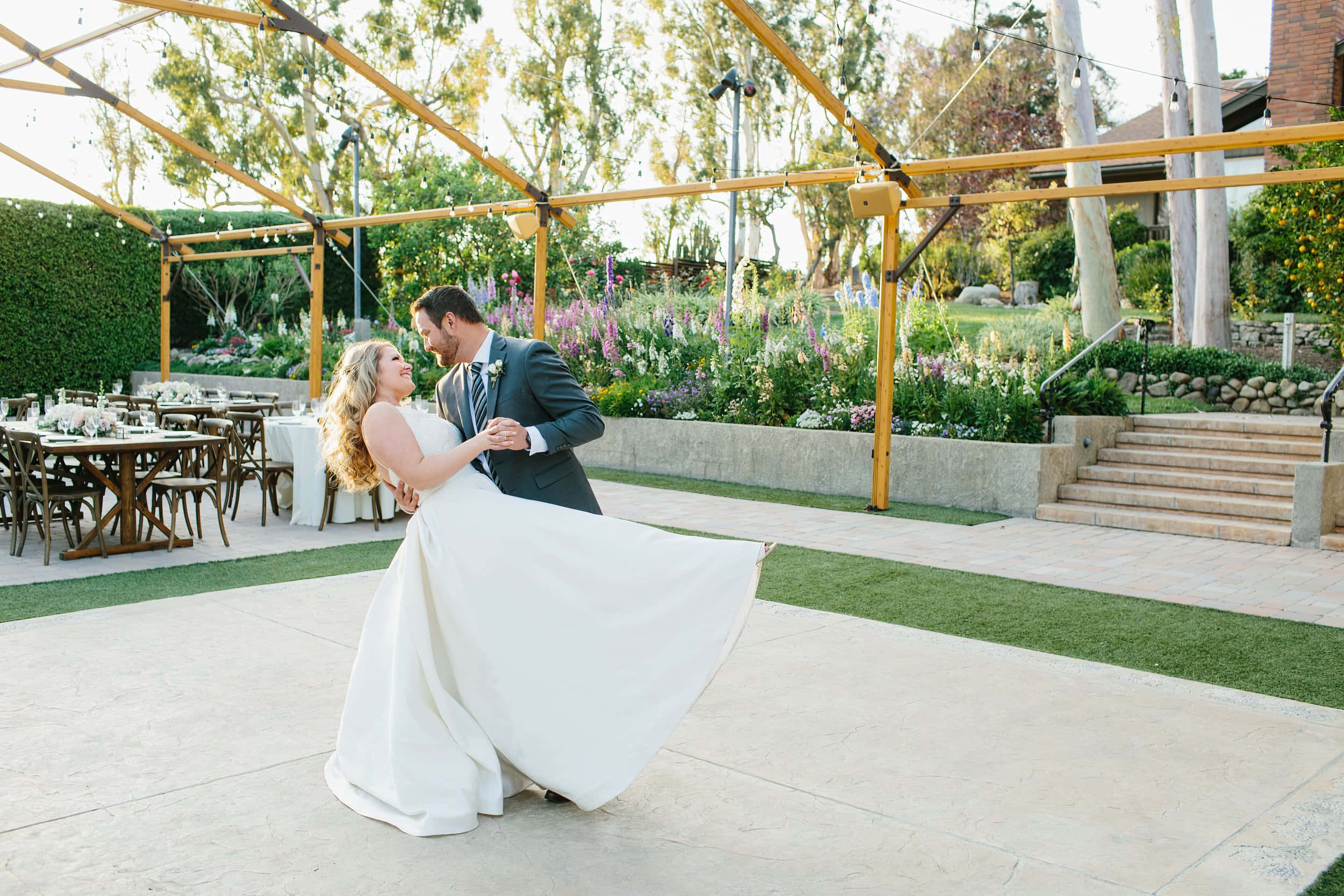Garden Wedding 桌布 壁紙 — 新娘和新郎在陽光普照的花園婚禮場地的木製涼亭下共享歡樂的舞蹈。