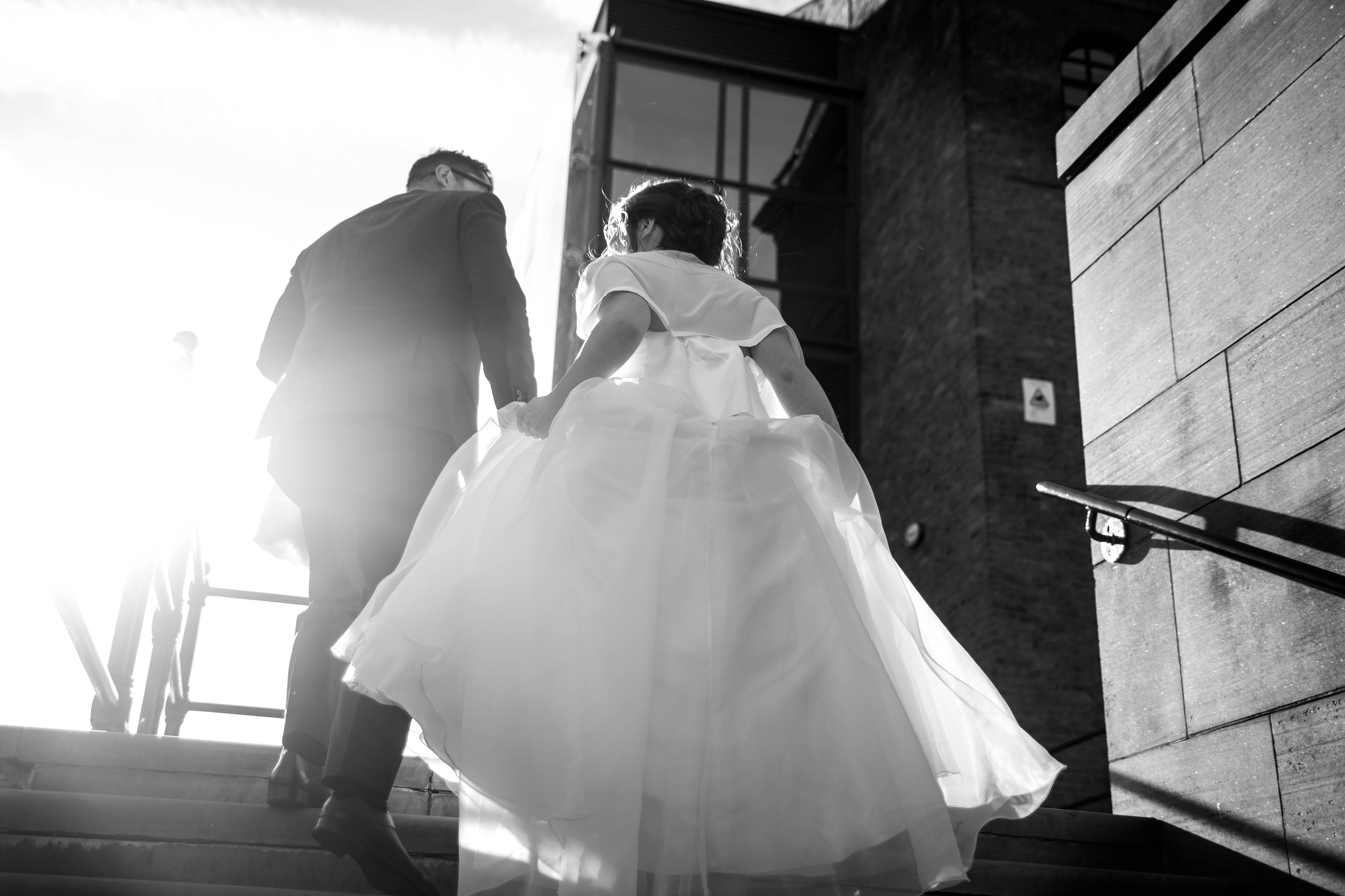 Groom 桌布 壁紙 — 新娘和新郎在黑白畫面中登上石階，戲劇性的背光投射出長長的影子。
