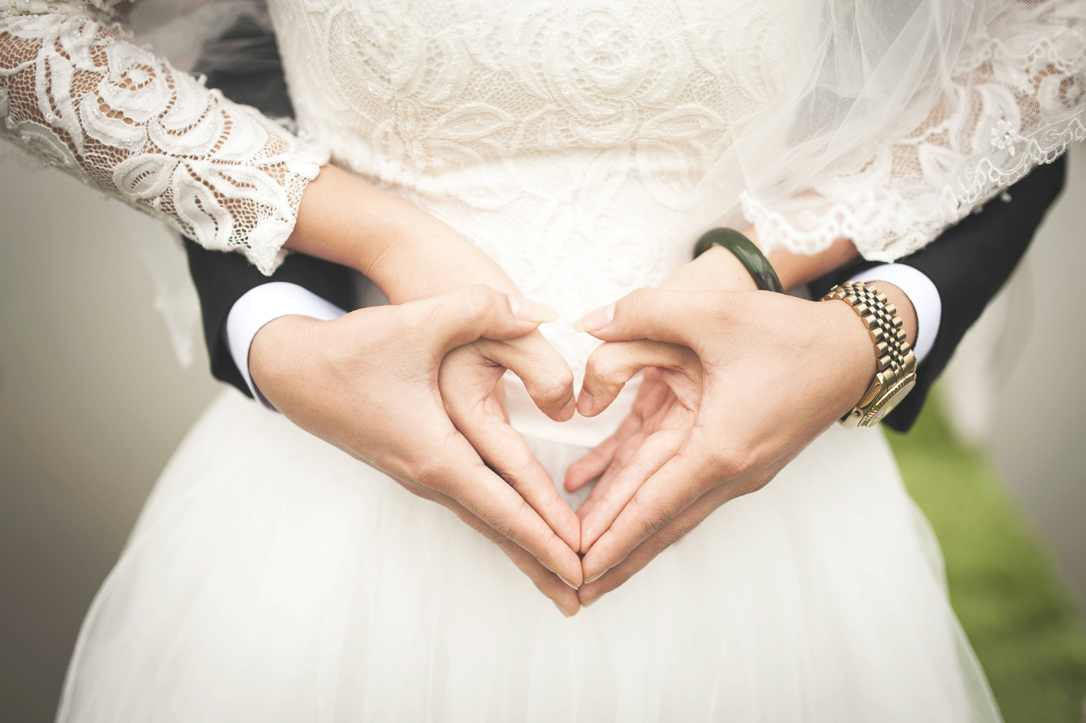 Wedding 桌布 壁紙 — 新娘和新郎用交織的雙手形成一個心形，背景柔和模糊。