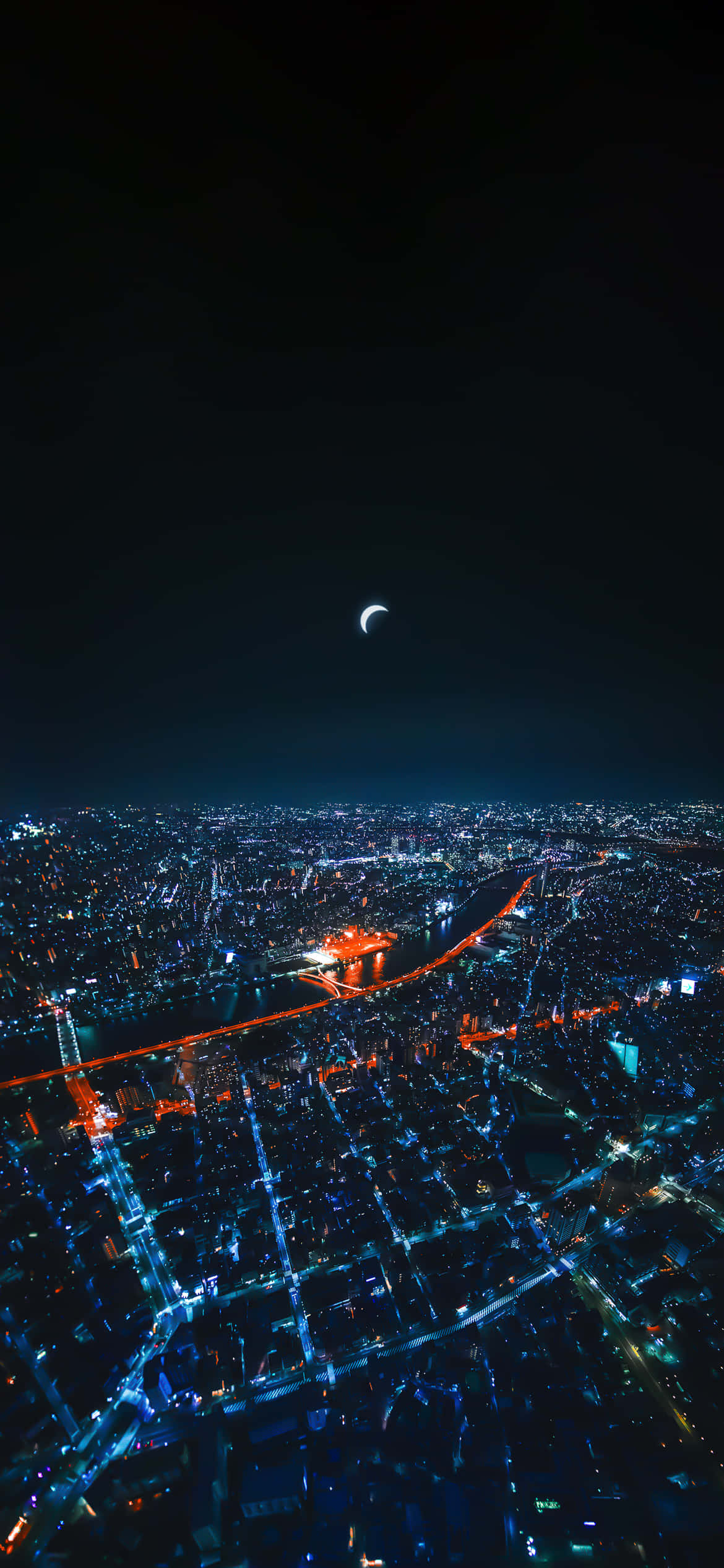 City Night 桌布 壁紙 — 新月下，一座廣闊城市在夜晚被藍色和橙色燈光照亮的鳥瞰圖。