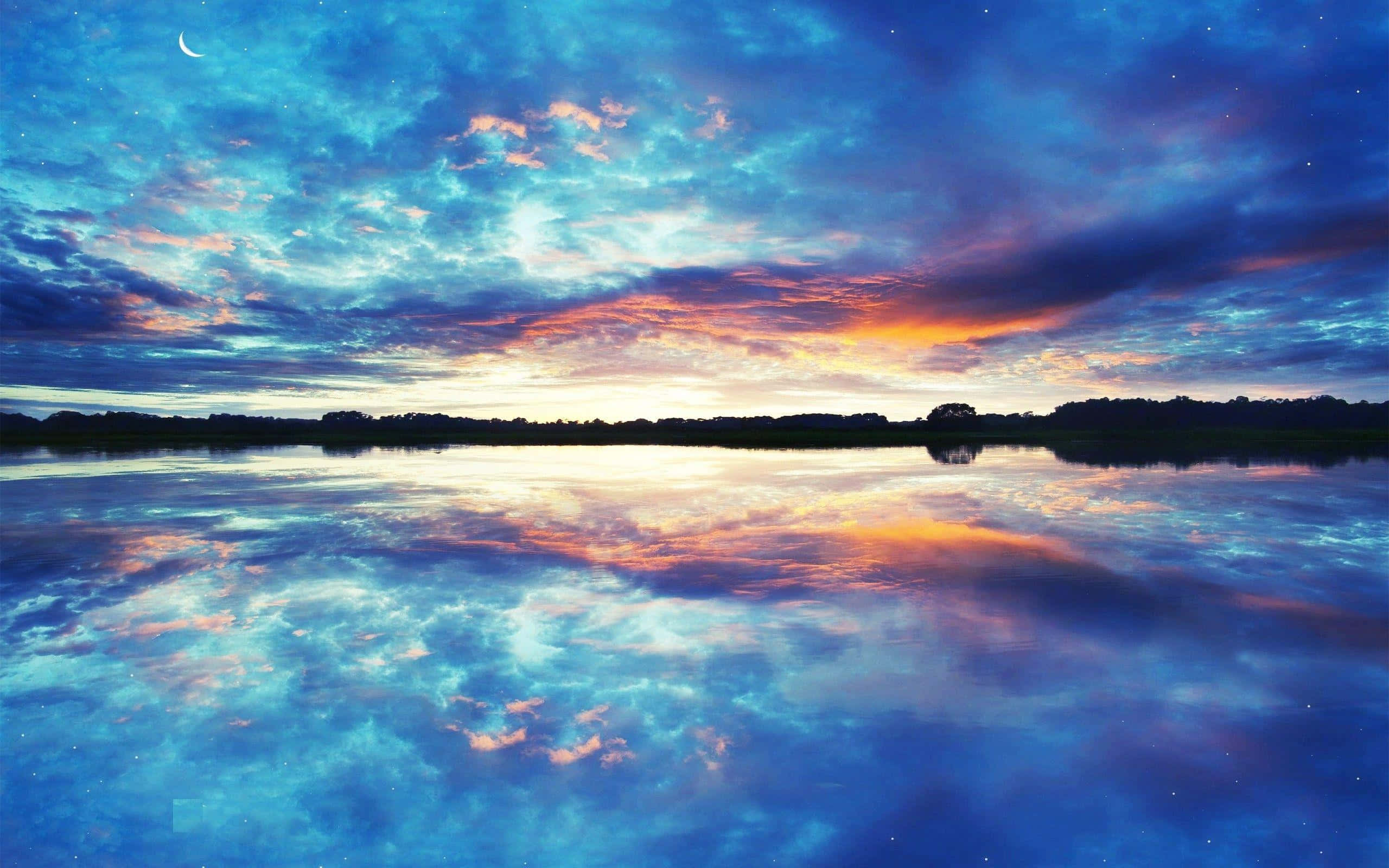 Sunset Reflection 桌布 壁紙 — 新月下，平靜的湖面完美映照出帶有鮮豔橙色和藍色雲朵的寧靜暮色天空。