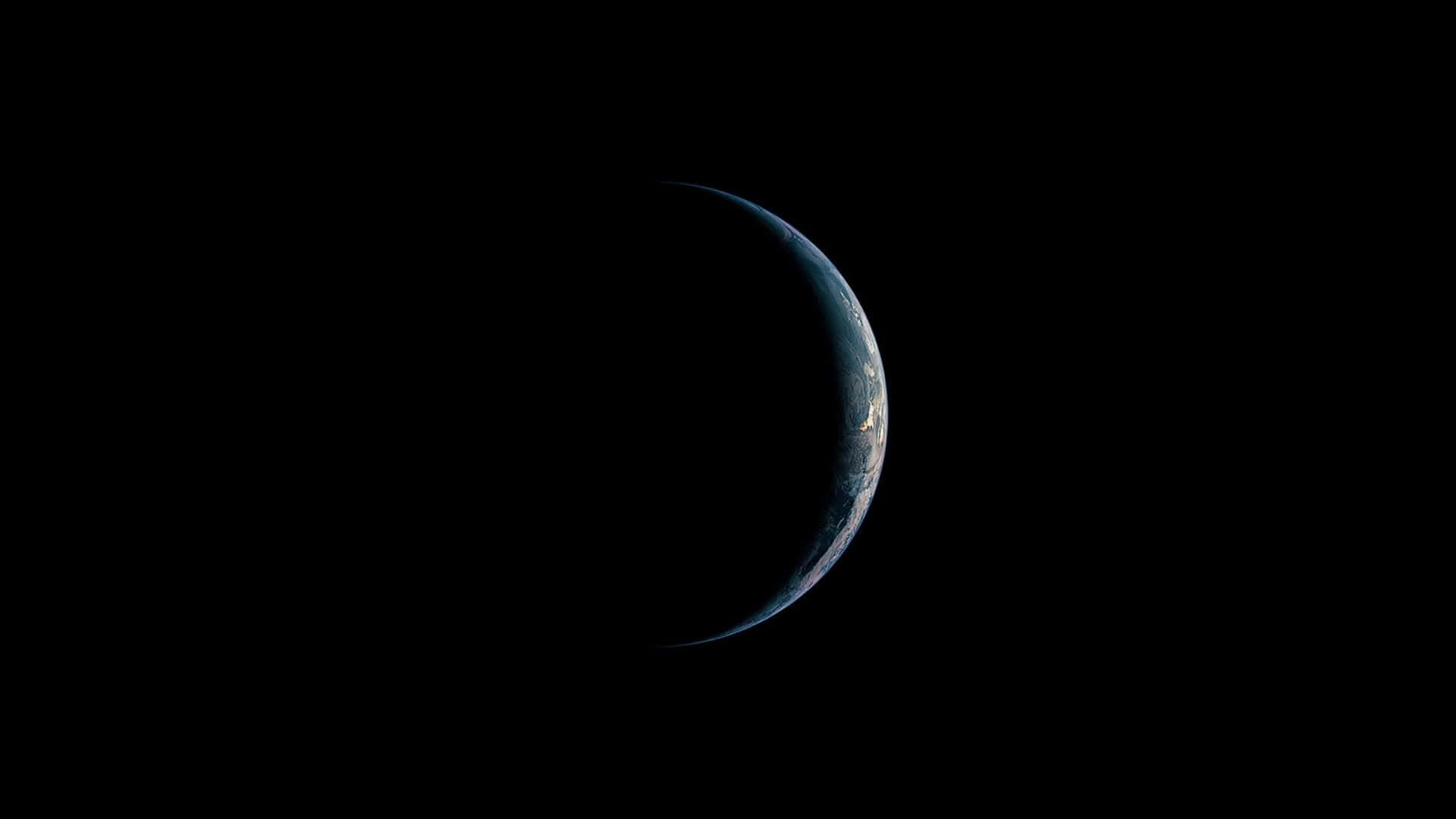 HD Amoled 桌布 壁紙 — 新月形的地球在廣闊的太空黑暗中微微發光，顯現出旋轉的藍色海洋和白色雲層。