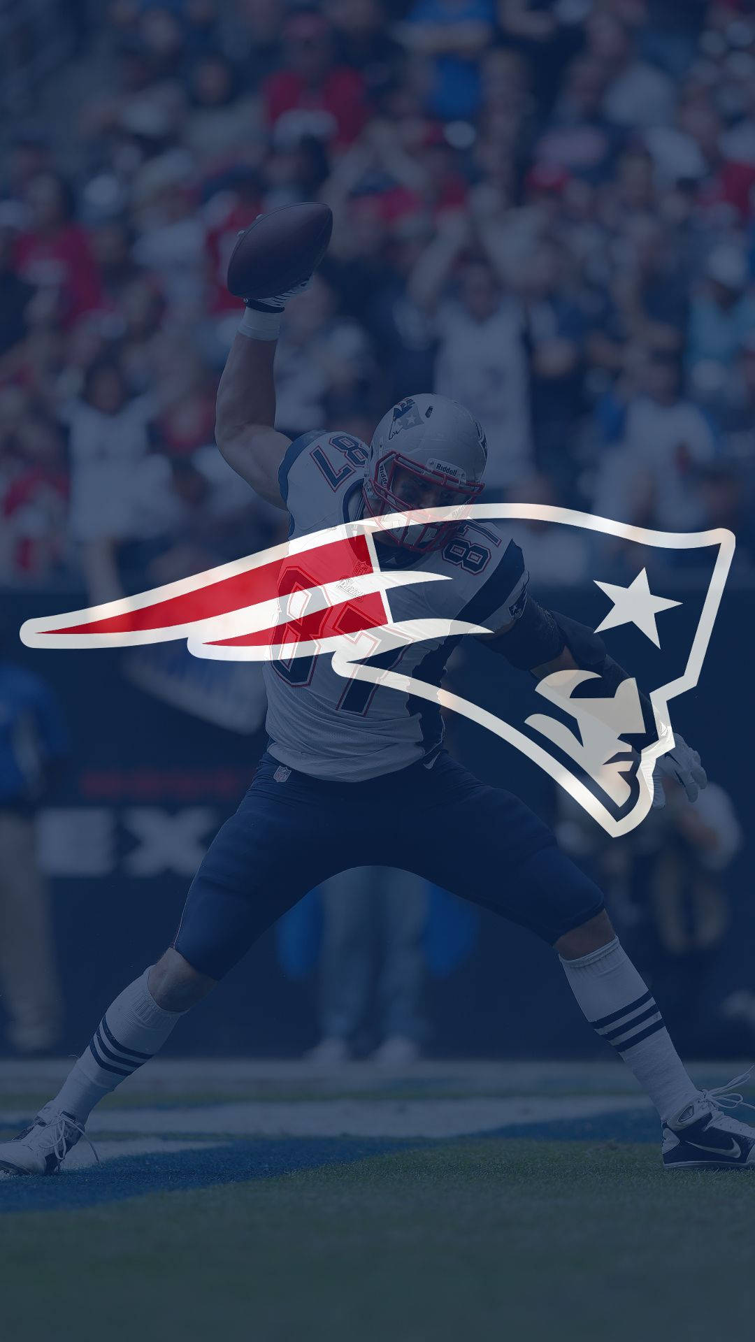 Patriots 桌布 壁紙 — 新英格蘭愛國者隊的足球運動員在場上比賽，球隊標誌疊加在上方。