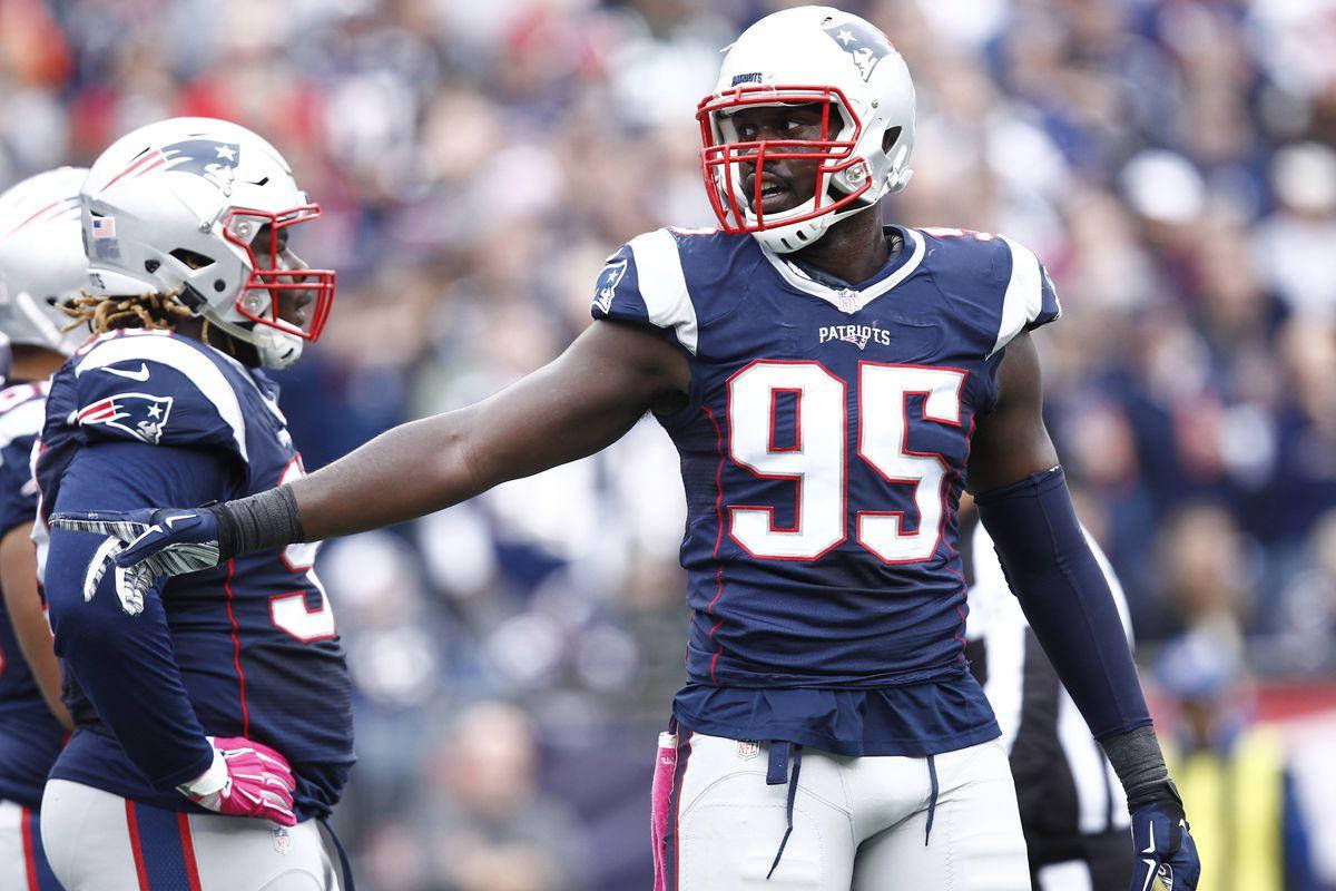 New England Patriots 桌布 壁紙 — 新英格蘭愛國者隊美式足球員95號身穿海軍藍和白色球衣，在陽光明媚的比賽日場上與隊友擊掌。