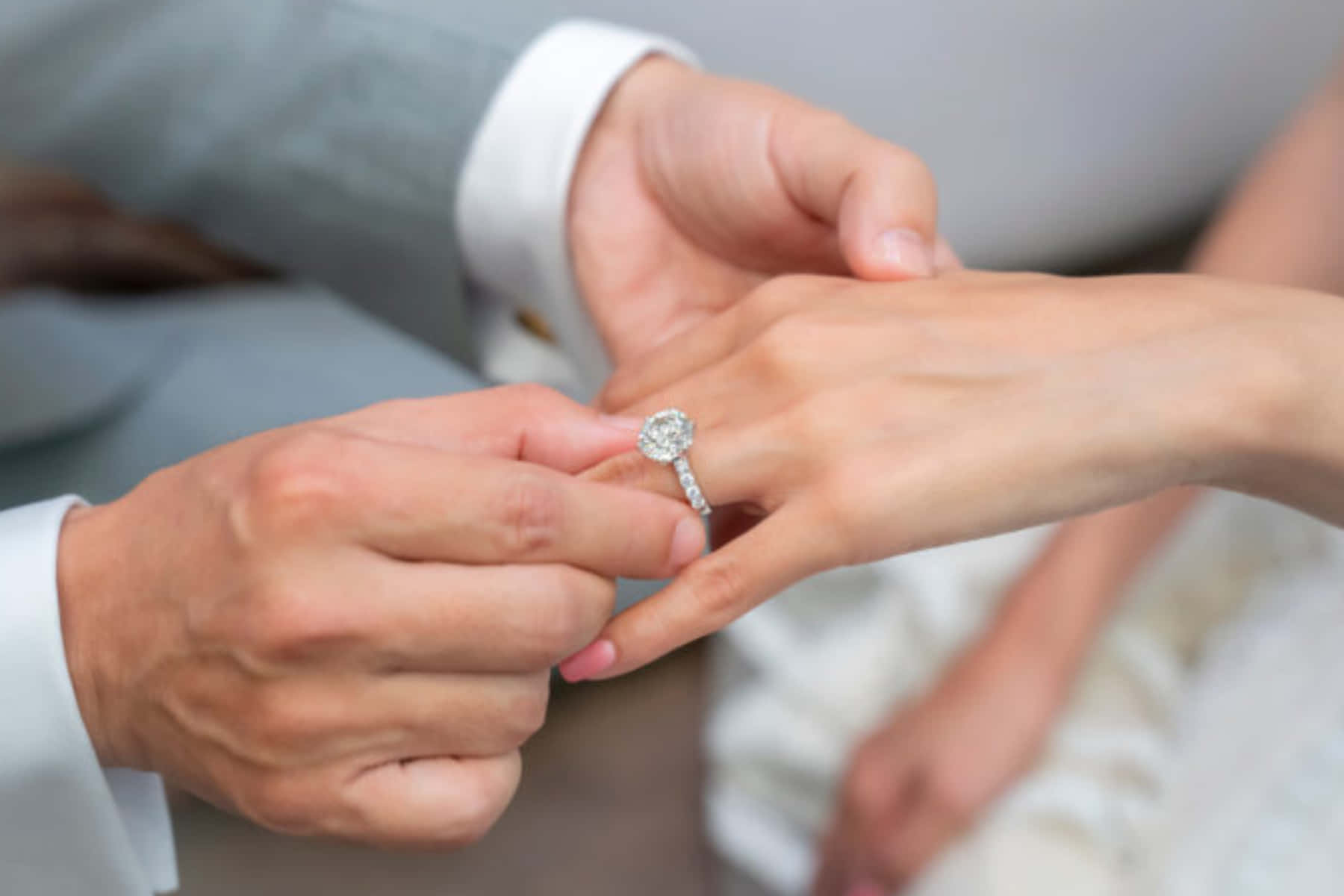 Marriage 桌布 壁紙 — 新郎溫柔地將閃爍的鑽石訂婚戒指戴在新娘的手指上，一個溫馨的婚禮時刻。
