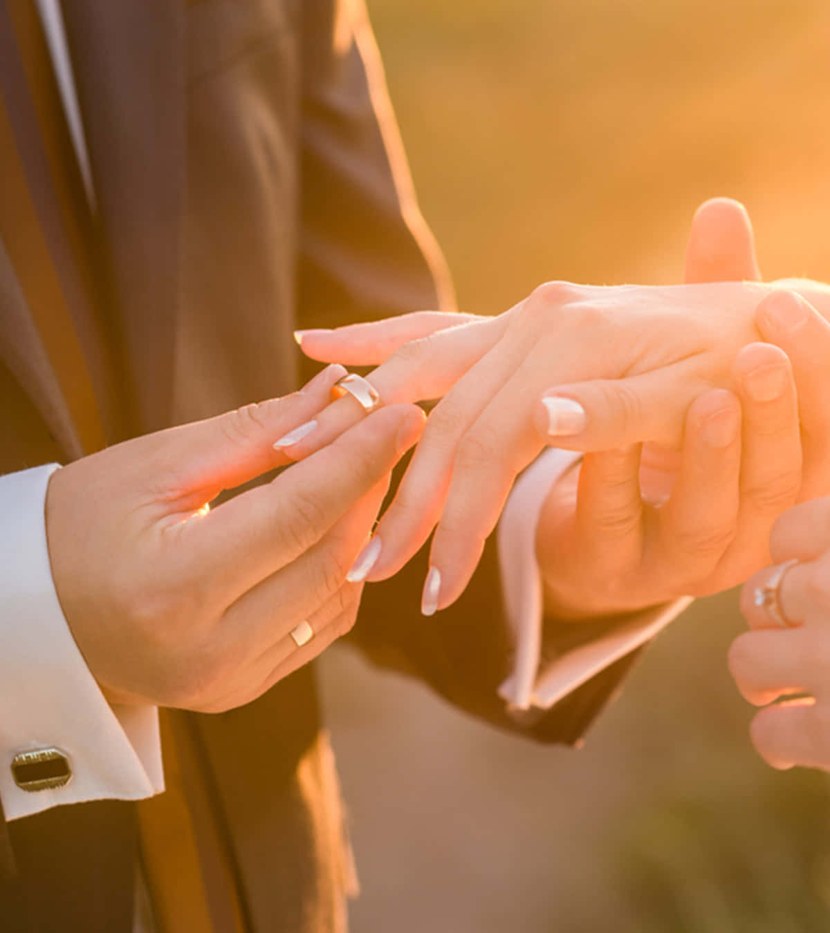 Marriage 桌布 壁紙 — 新郎輕輕地將結婚戒指戴在新娘的手指上，金色的陽光溫暖地沐浴著他們的雙手。