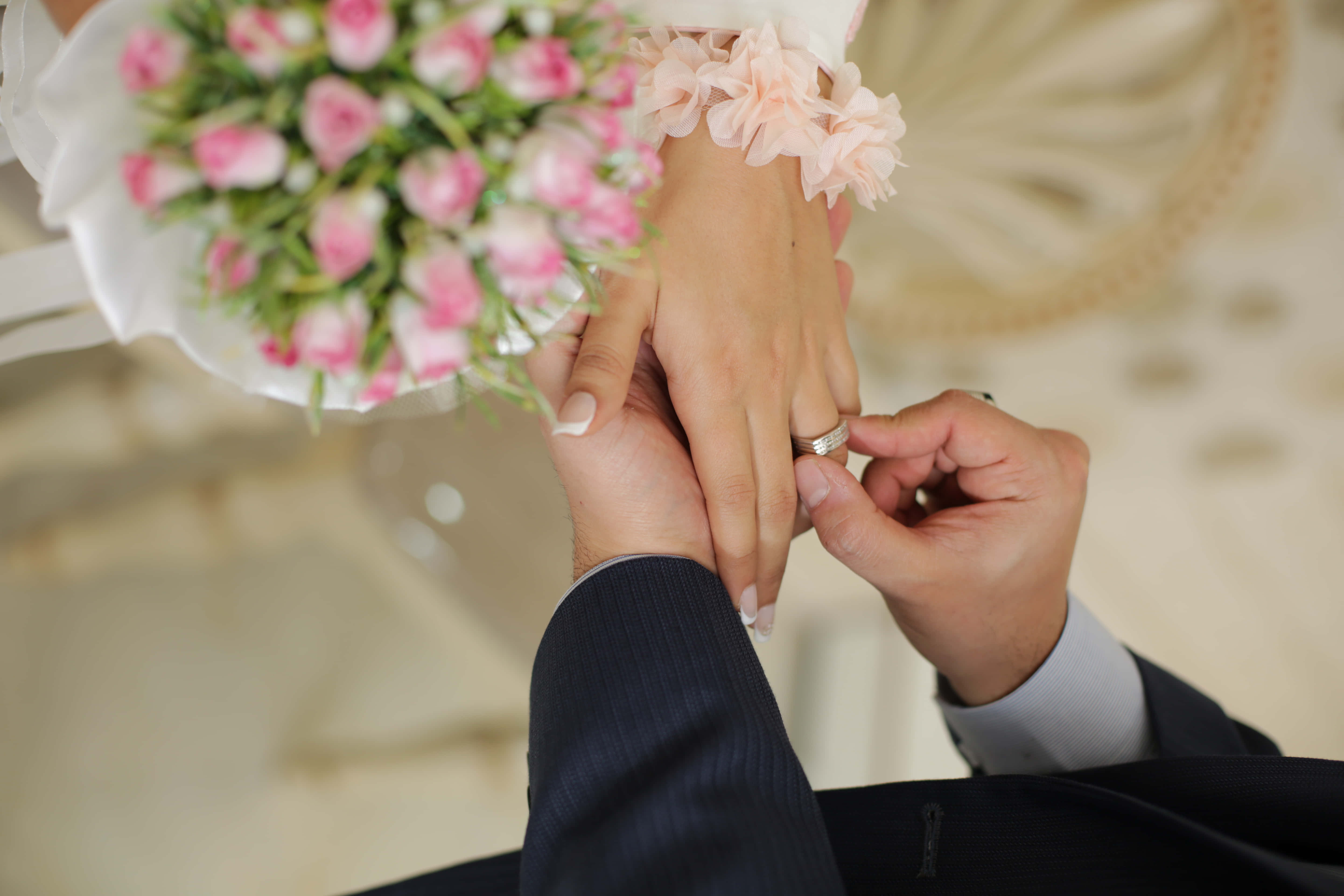 Wedding 桌布 壁紙 — 新郎輕輕地將結婚戒指戴在新娘的手指上，而她正拿著一束粉紅玫瑰。
