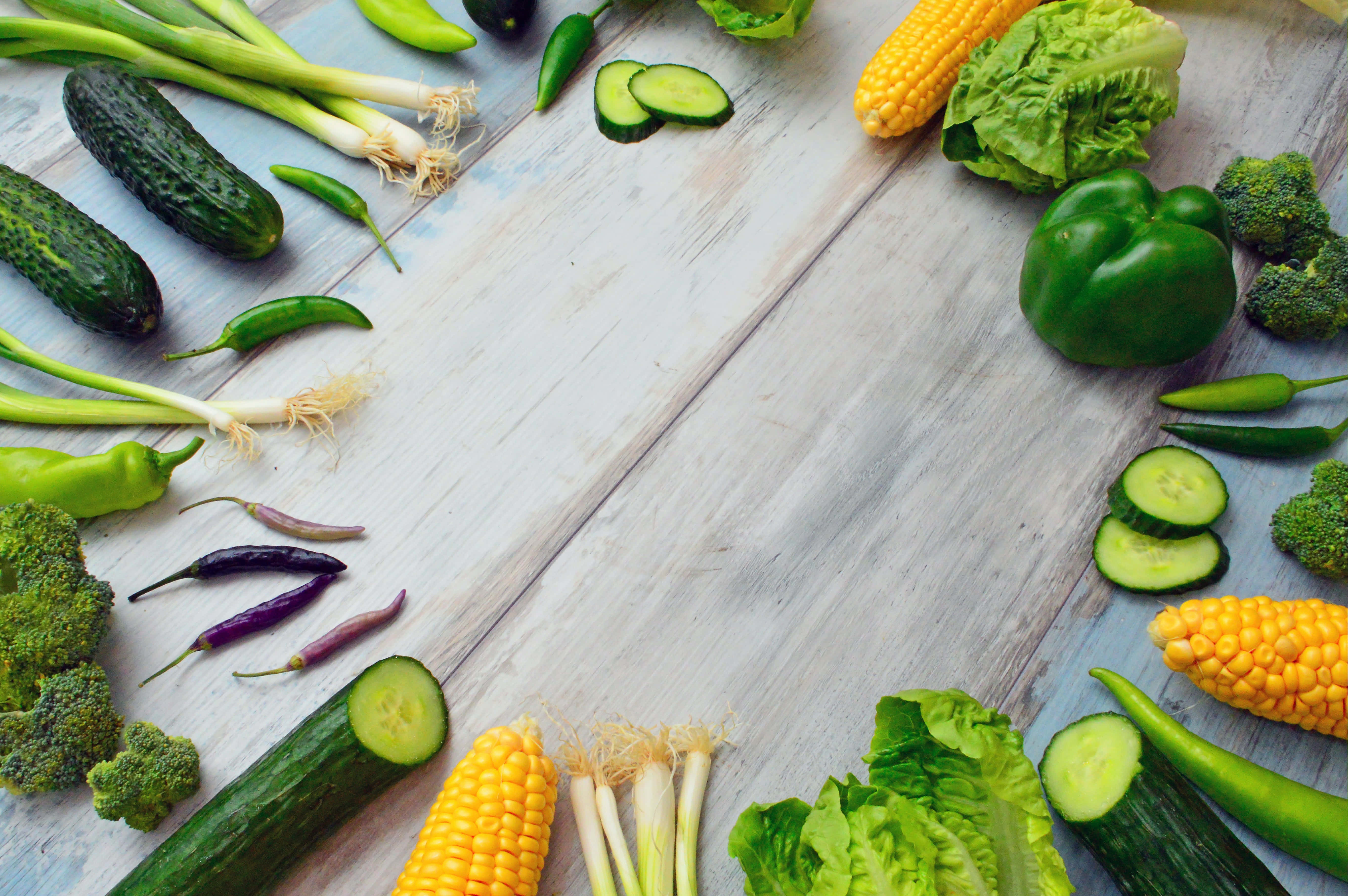 cucumber 桌布 壁紙 — 新鮮充滿活力的蔬菜，如玉米、西蘭花和黃瓜，在風化的木質表面上排列成色彩繽紛的邊框。