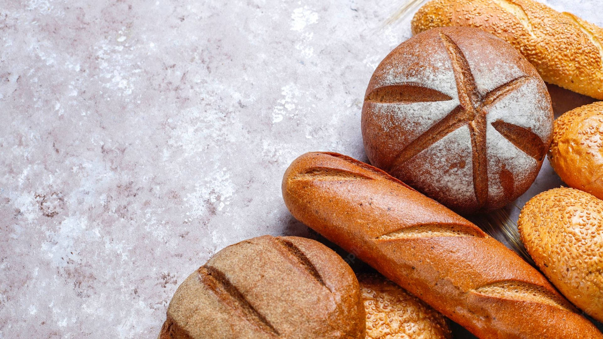 麵包 桌布 壁紙 — 新鮮出爐的工匠麵包，金黃色的外皮上撒有麵粉，放在有紋理的石頭表面上。
