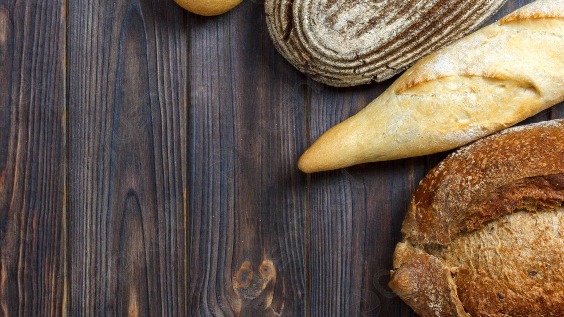 Bread 桌布 壁紙 — 新鮮出爐的工匠麵包，金黃色的外皮，放在深色鄉村風木質表面上。