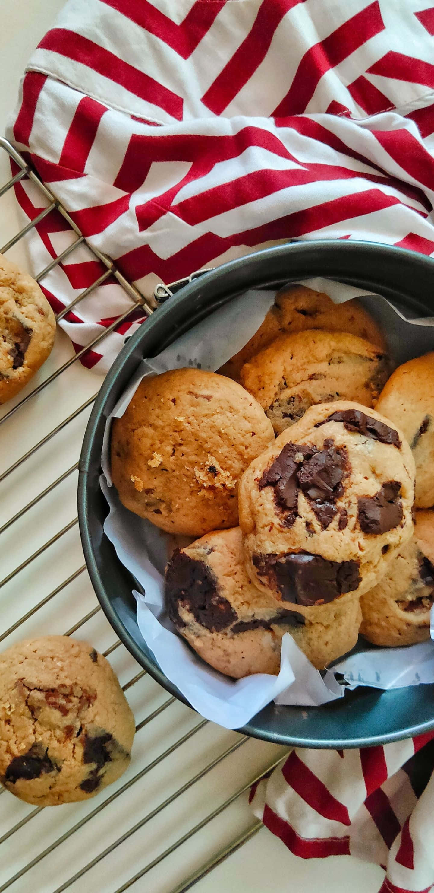Pixel 3xl Cookies 桌布 壁紙 — 新鮮出爐的巧克力豆餅乾放在鋪有烘焙紙的金屬碗中，置於紅白條紋布上。