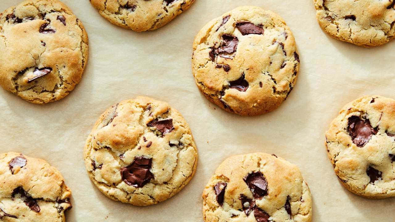 720p Cookies 桌布 壁紙 — 新鮮出爐的巧克力餅乾，金黃邊緣，放在烘焙紙上。